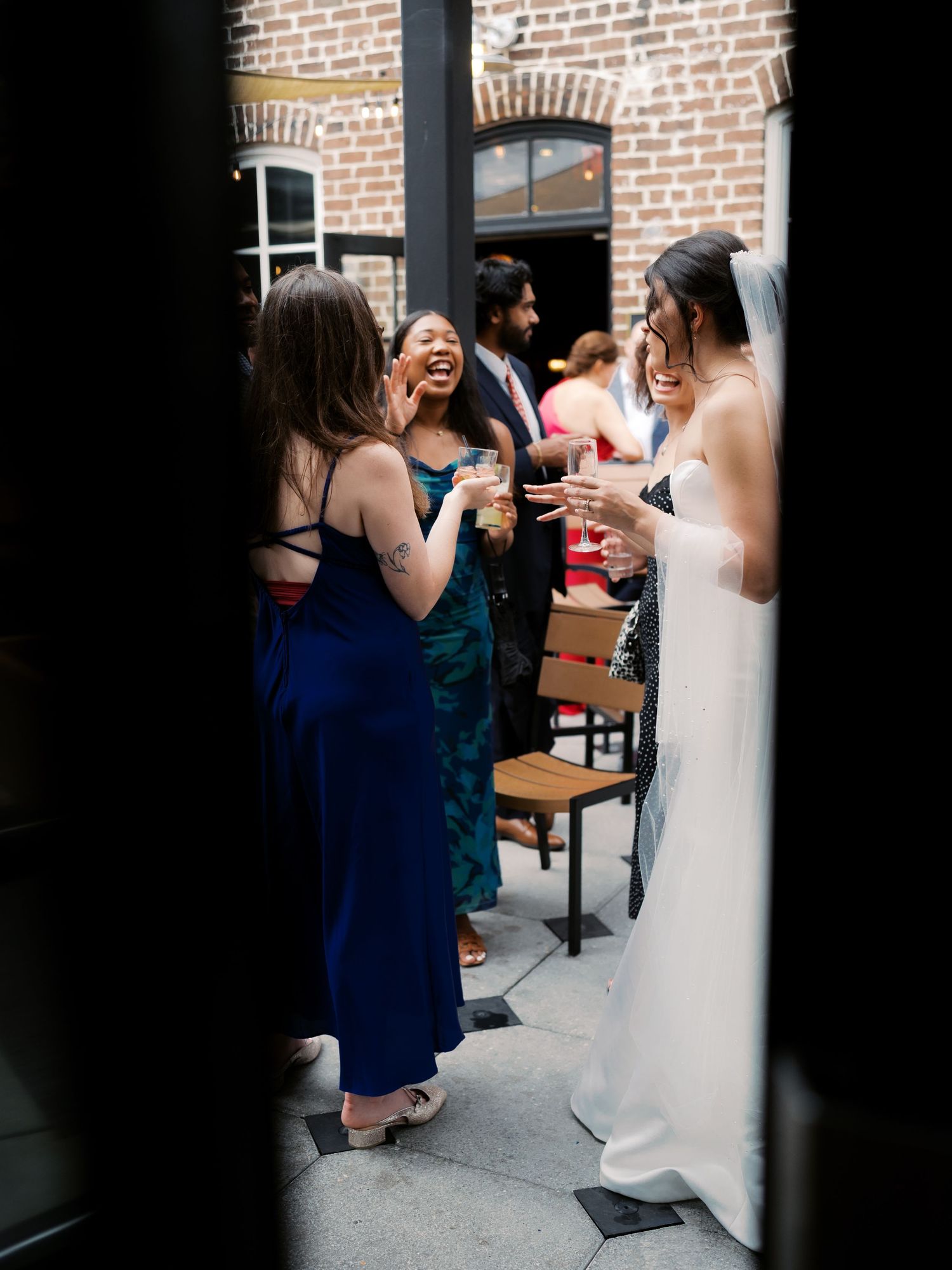 Wedding reception guests mingle in a rustic brick-walled venue.