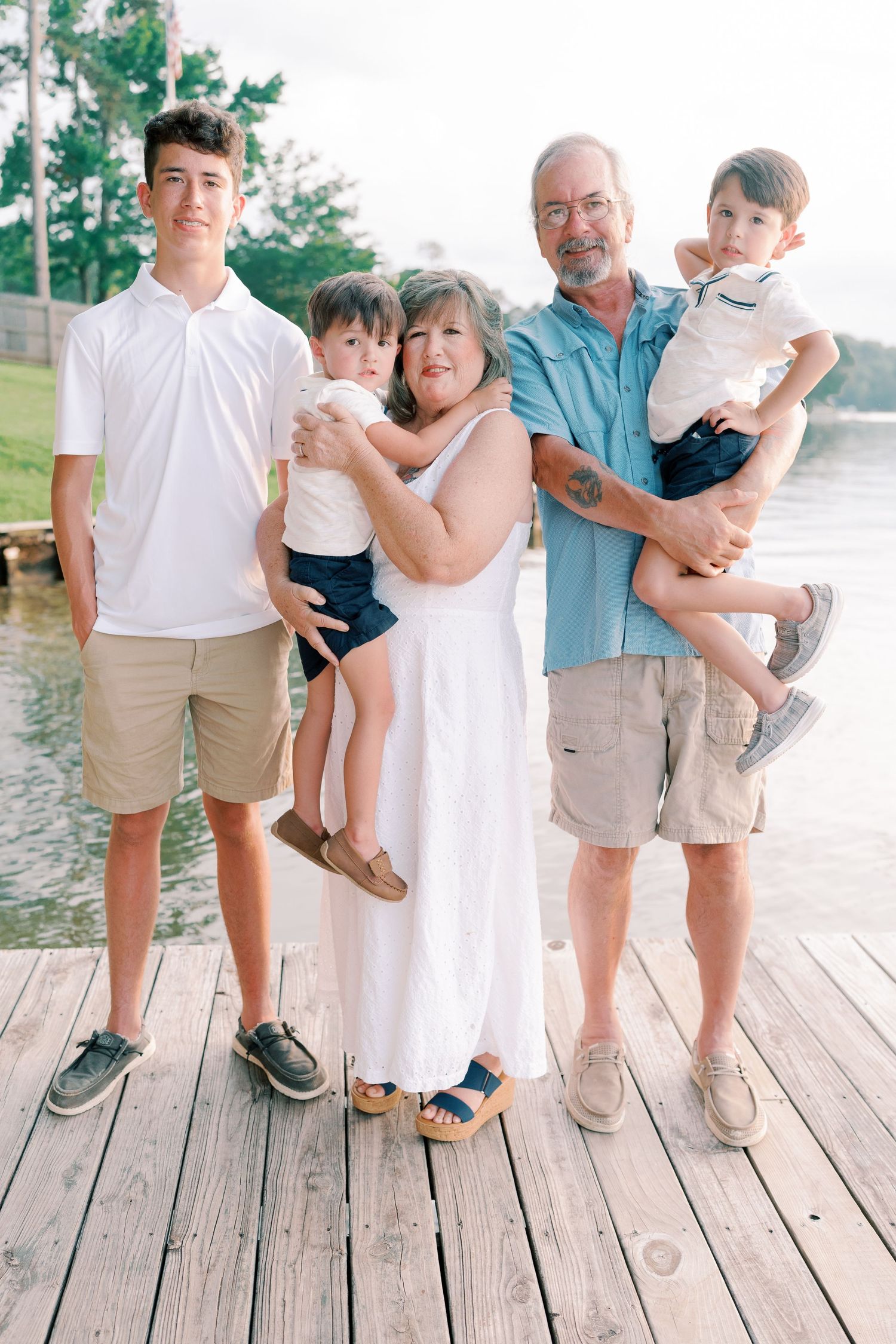 Family members' feet lined up on wooden dock showing casual summer footwear.