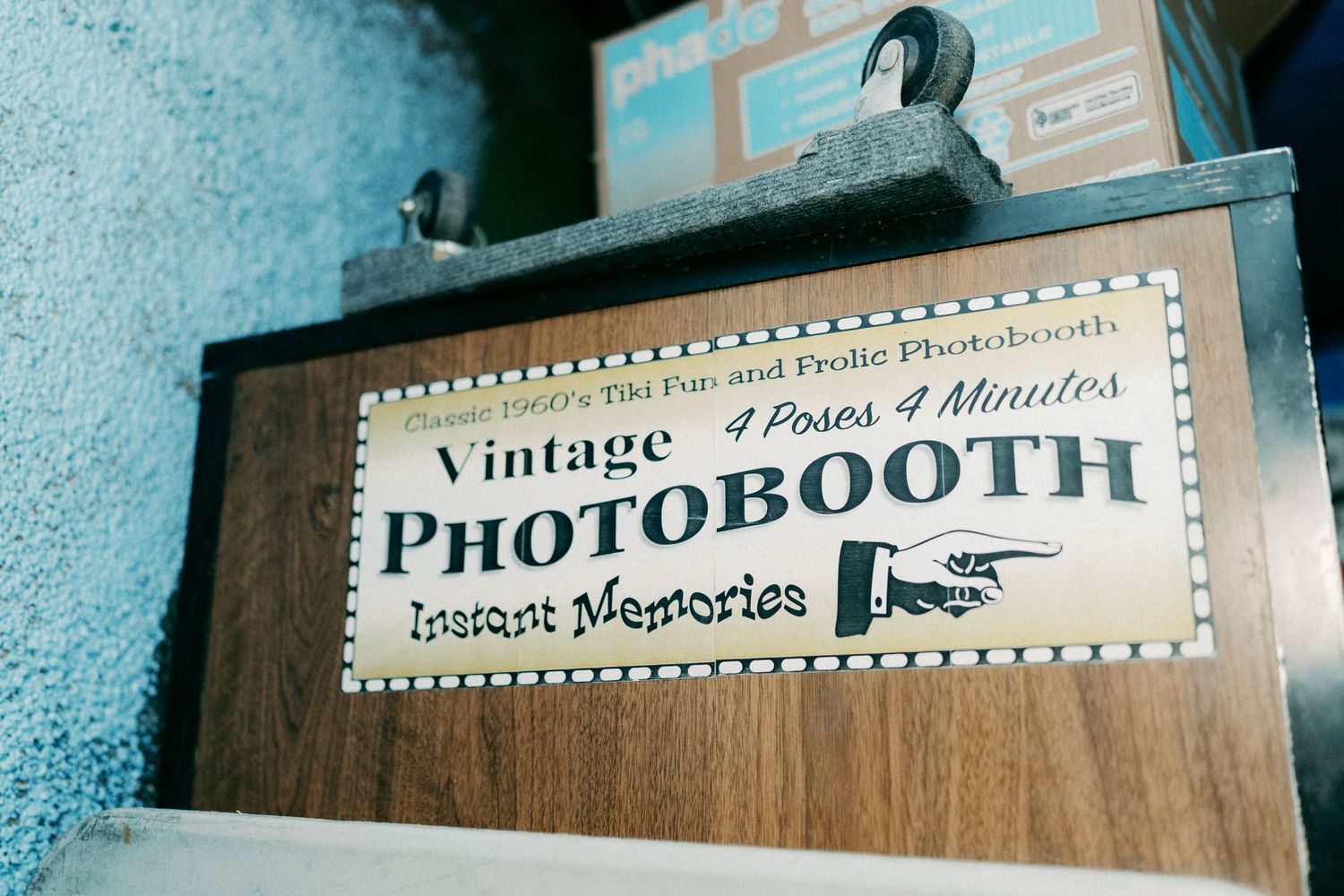 A vintage photo booth sign mounted on a wall.