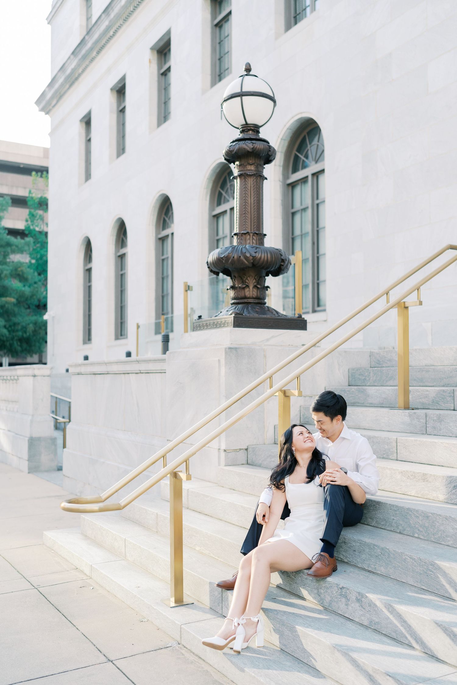 Couple sharing intimate moments on elegant stone steps with ornate lamp post.