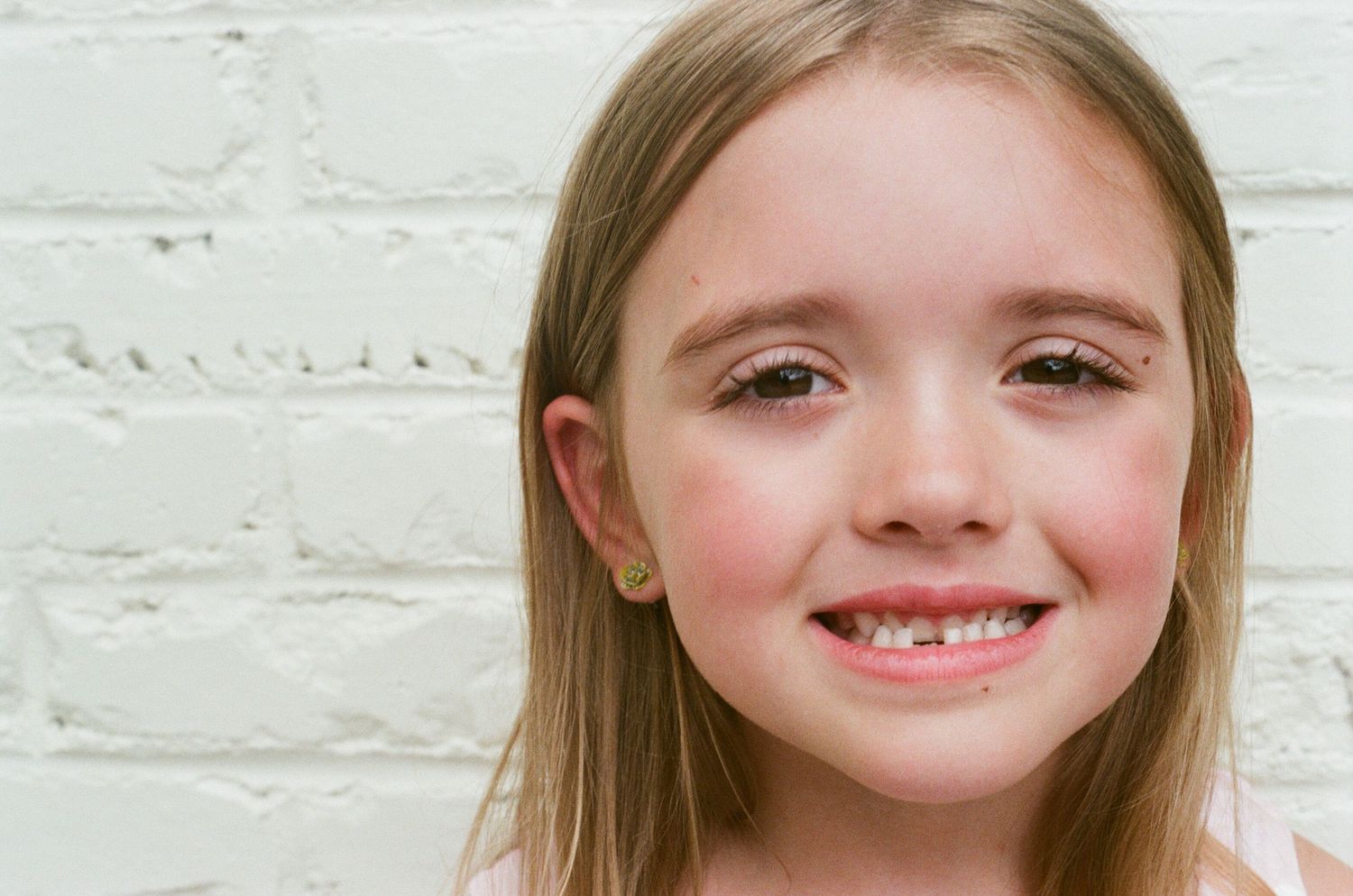 Close-up portrait against white brick wall.