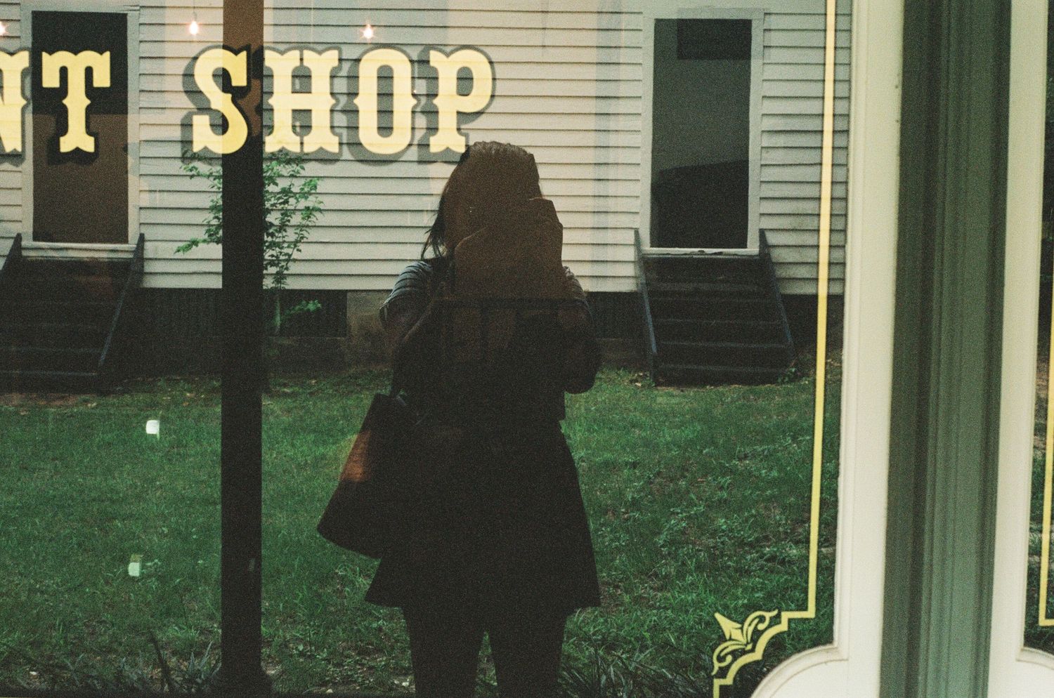 Vintage style shop front with white siding and dark signage.
