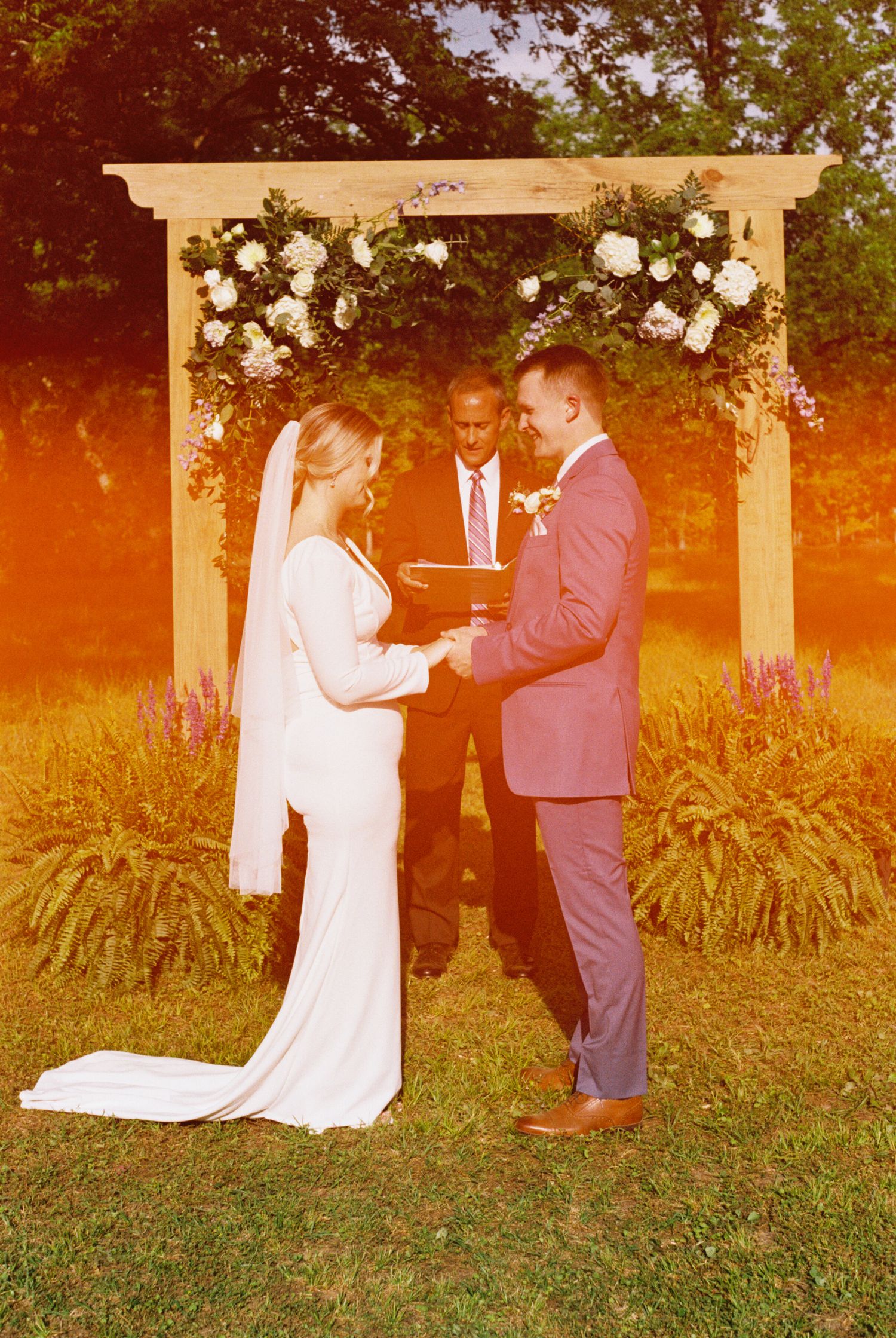 Wedding ceremony sequence under a floral arch during golden hour sunset.