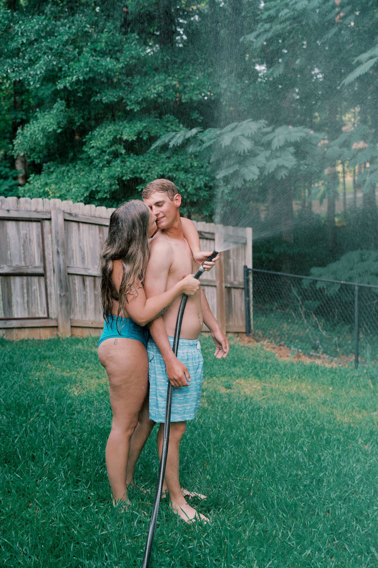 Candid moment of a couple laughing while playing with water outdoors.