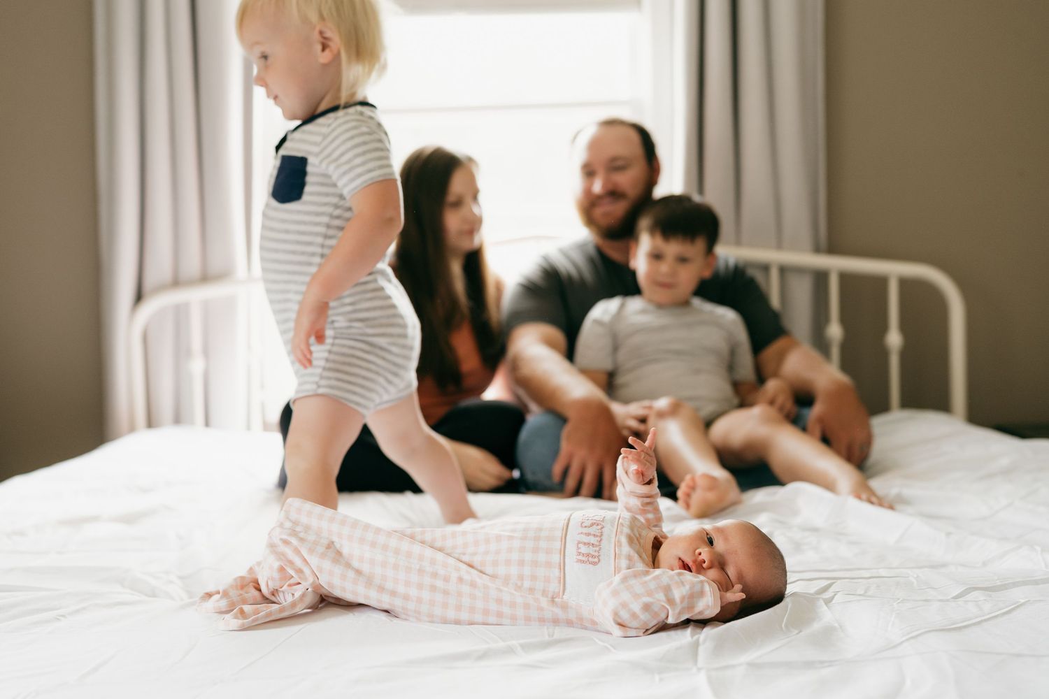 Intimate family moments captured on white bedding during indoor photoshoot.