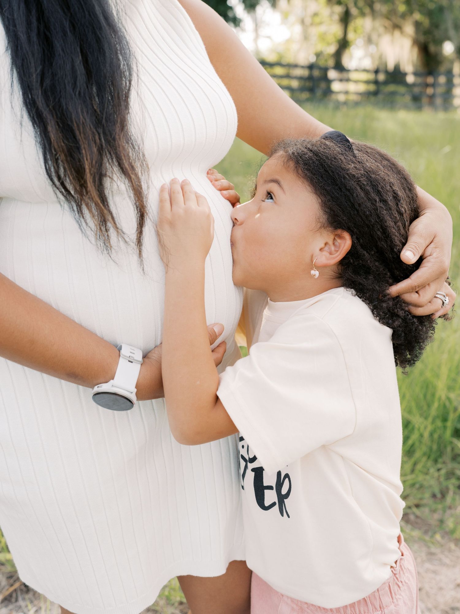 An intimate family photo shoot moment captured in soft natural lighting outdoors.