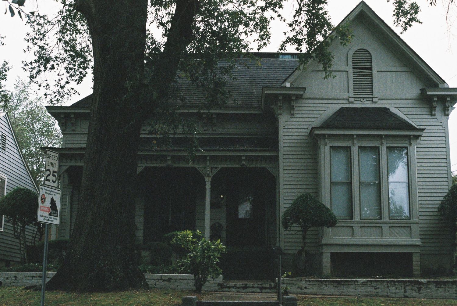 Row of vintage white Victorian houses with similar architectural features along a residential street.
