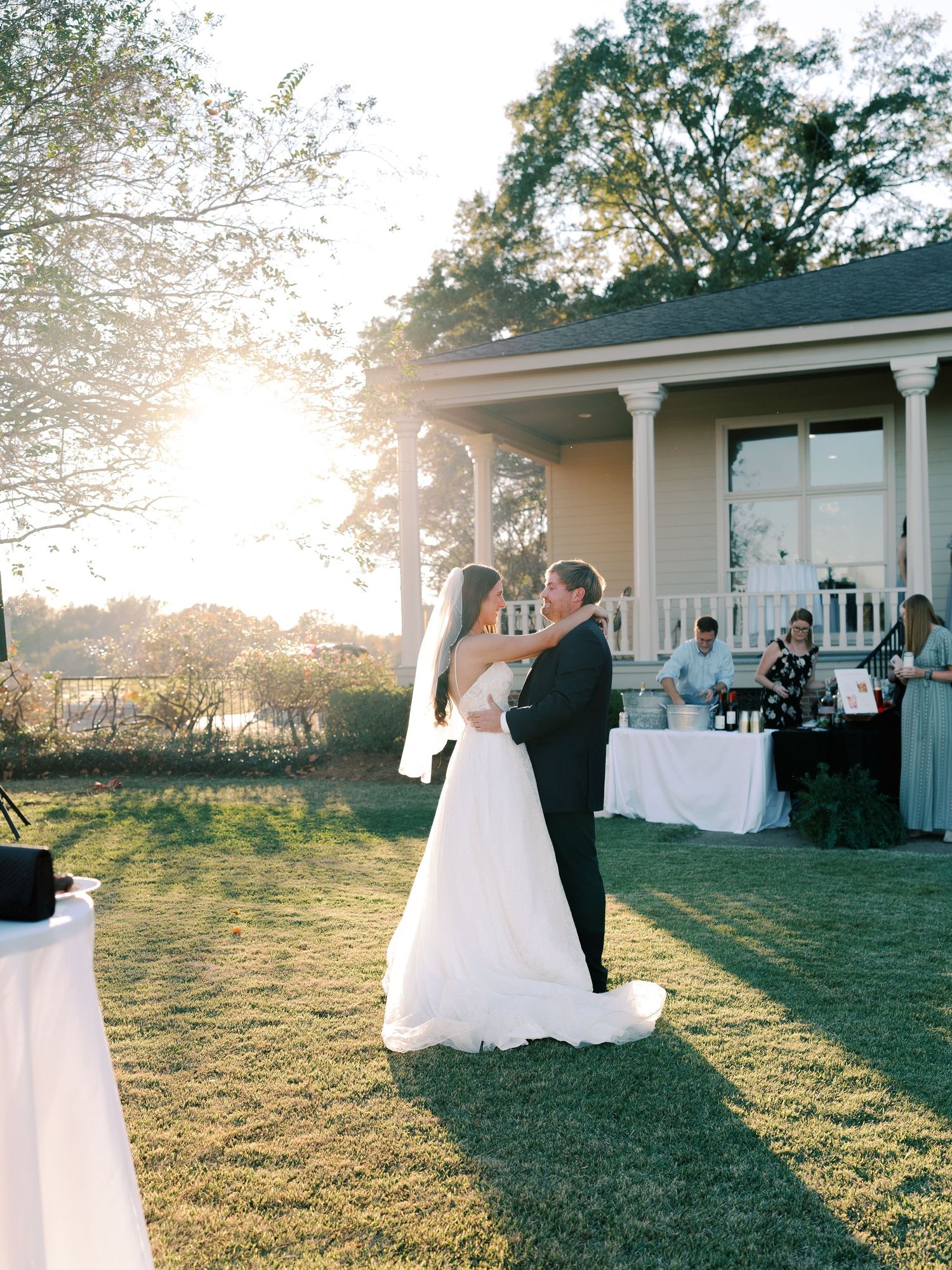 Wedding celebration at sunset outside a charming white colonial-style venue with covered porch.