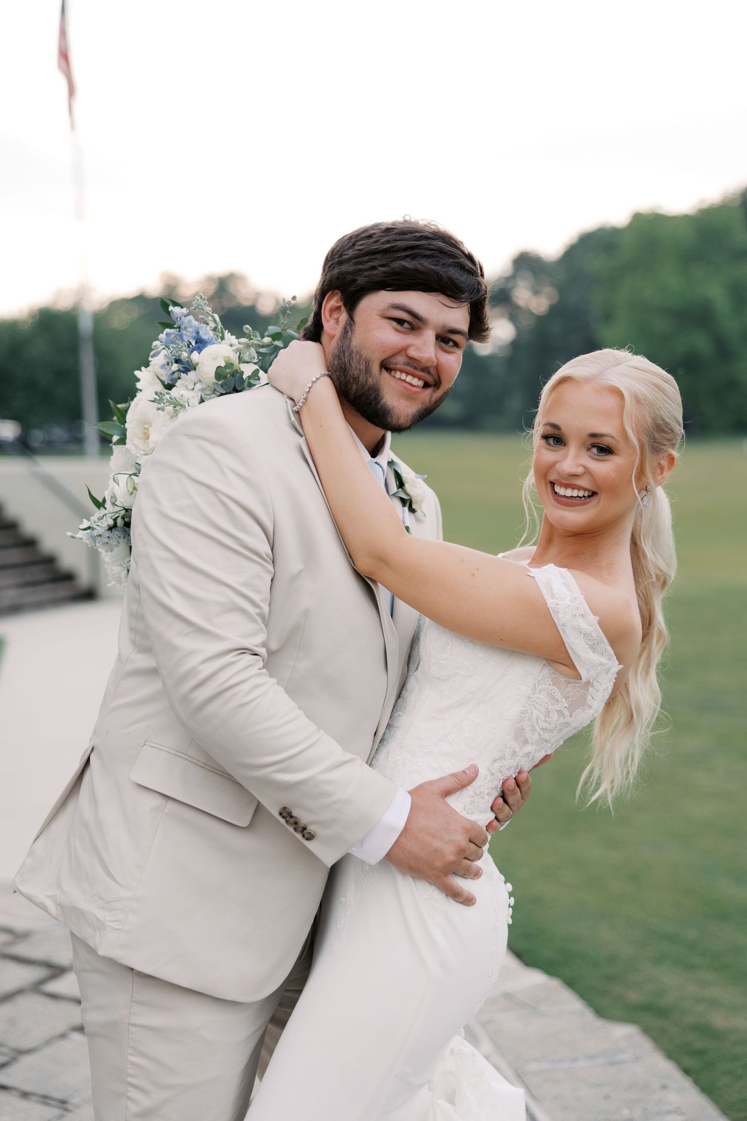 Joyful wedding couple embracing and laughing in cream colored attire.