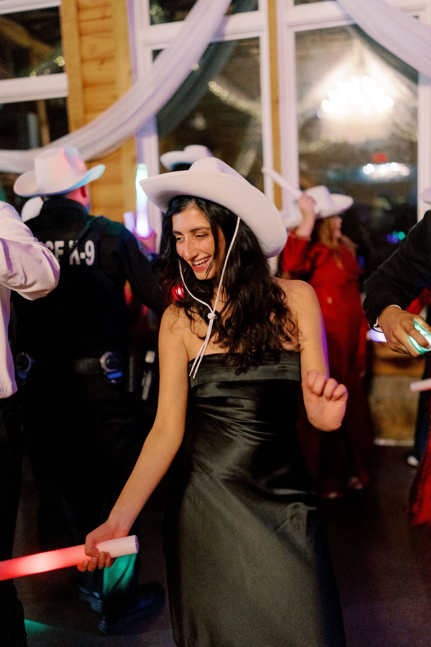 Party guests dancing under purple lighting and white fabric decorations.