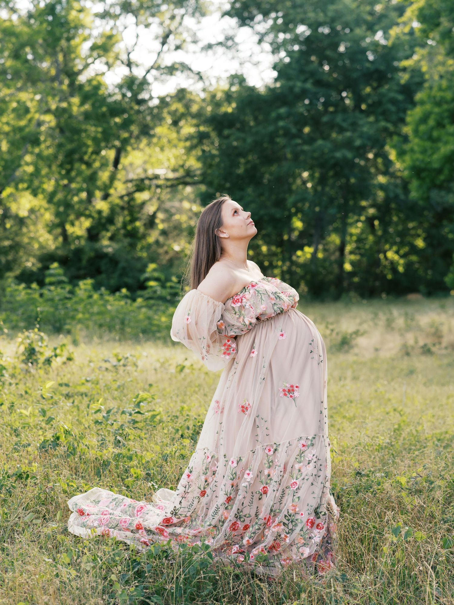 Flowing dress with floral embellishments creates movement against natural meadow backdrop.