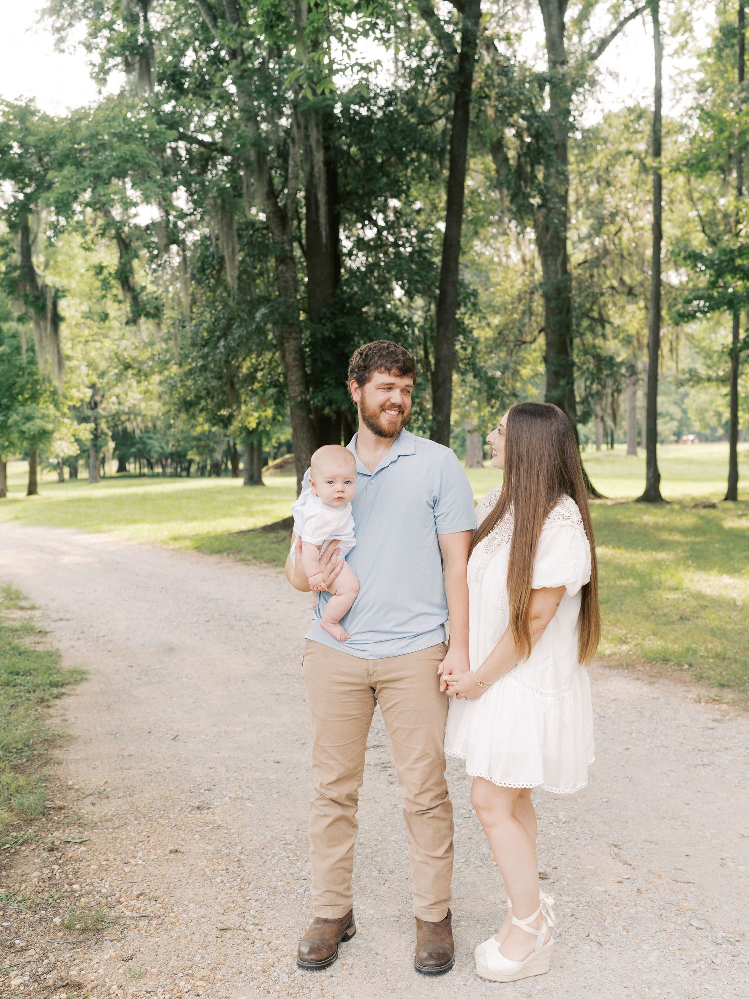 Three people walk together on a serene nature path surrounded by green trees.