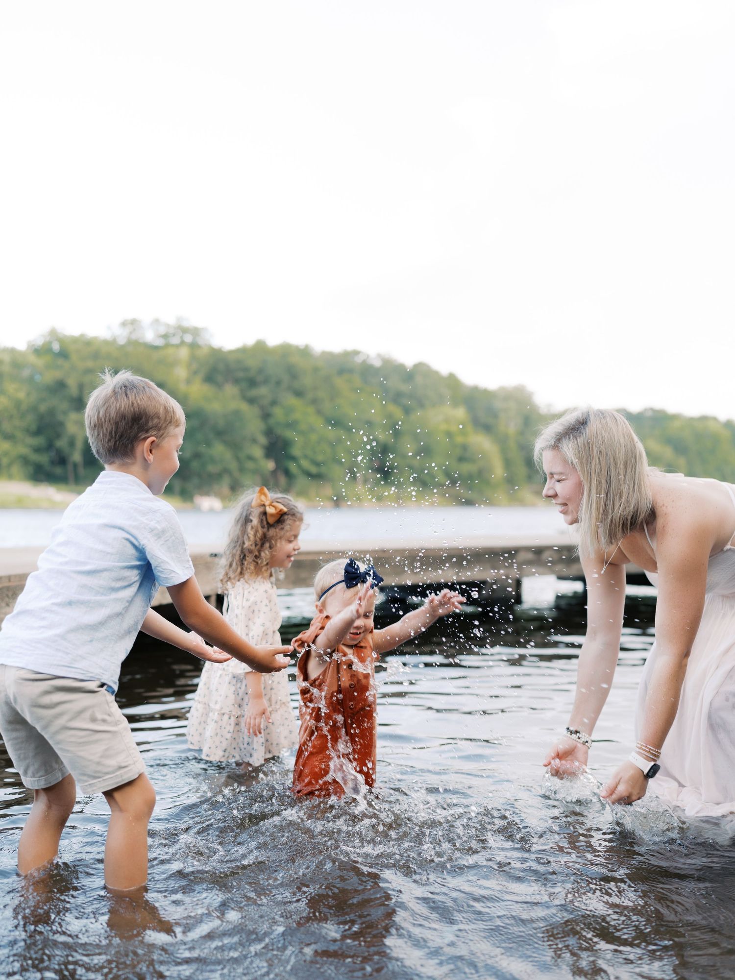 Family creating joyful water splashes while playing in a river on a summer day.