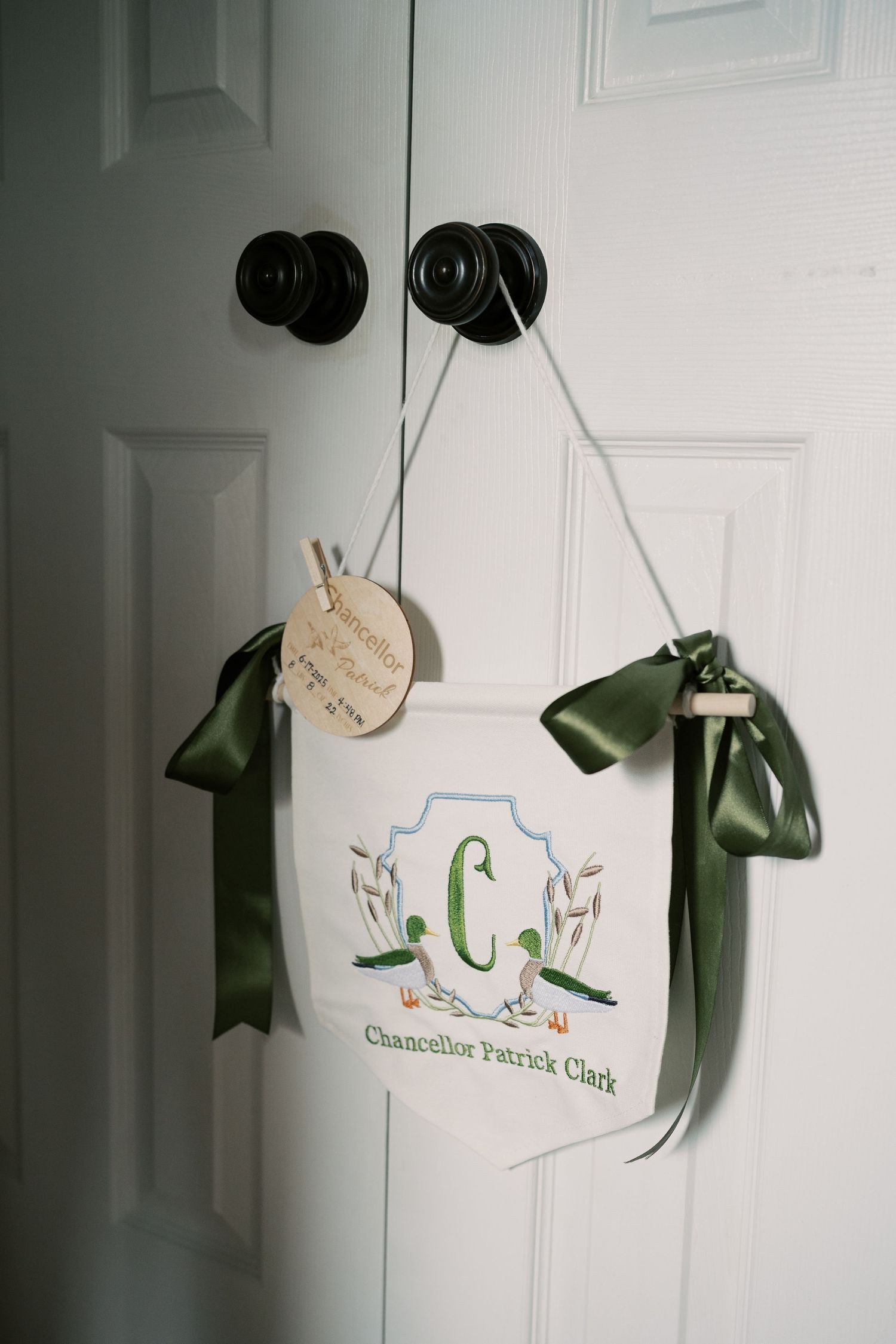 Decorative door hangers with monogram designs in soft blue and green tones.