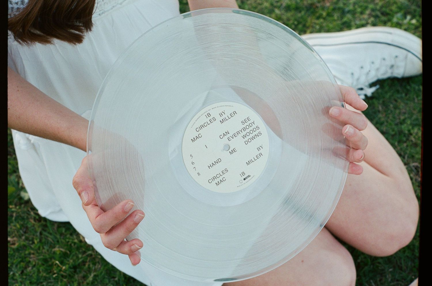 Hands holding clear vinyl records in outdoor setting.