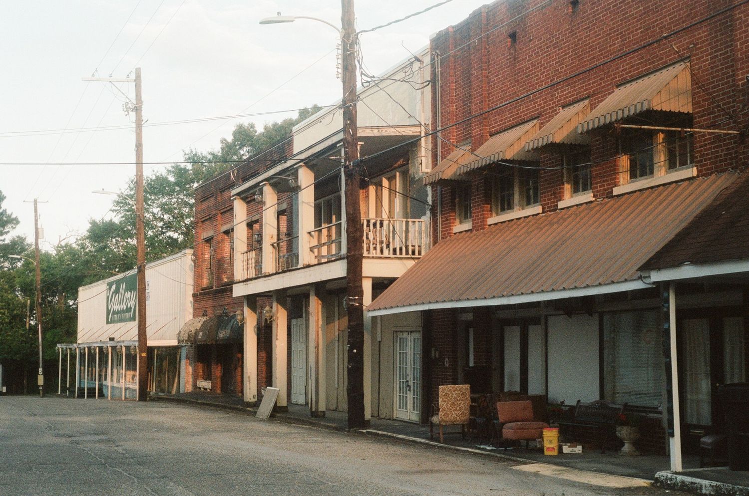 Row of old brick storefronts along a sloping street in a small town.