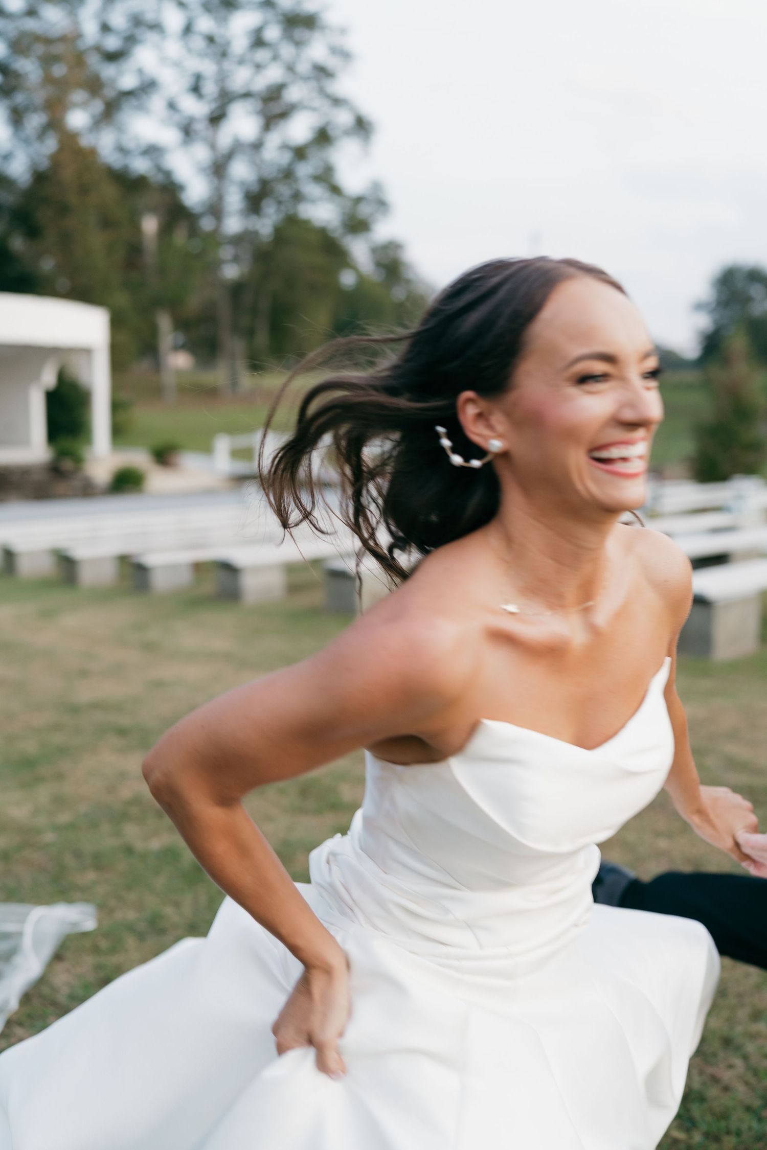 Joyful bride in white dress twirling and dancing outdoors.