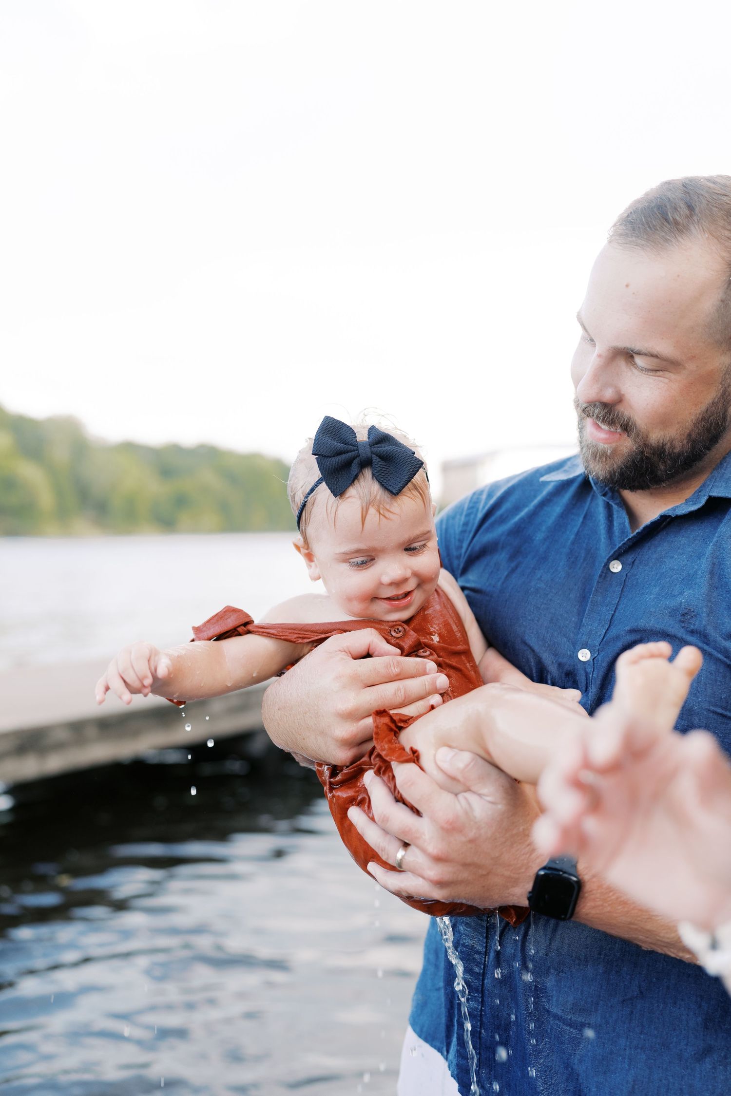 Close-up of hands examining a small red crayfish caught in river water.
