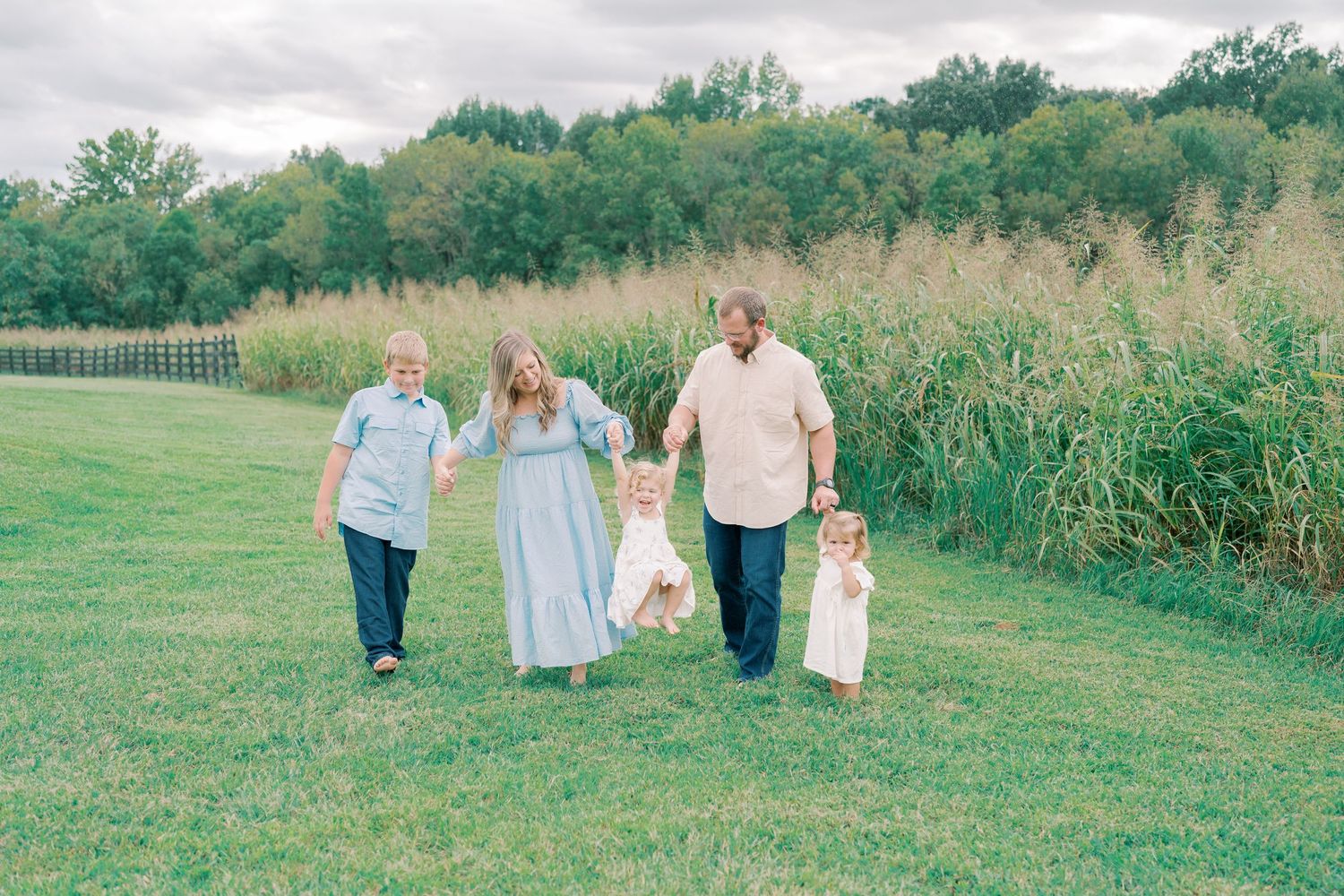 Group walks together through a scenic field with tall grass and trees in the background.