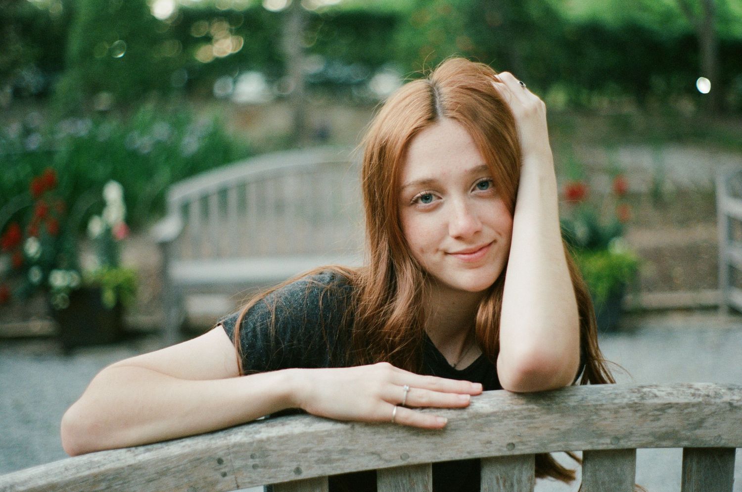 Person resting on wooden railing in outdoor garden setting.