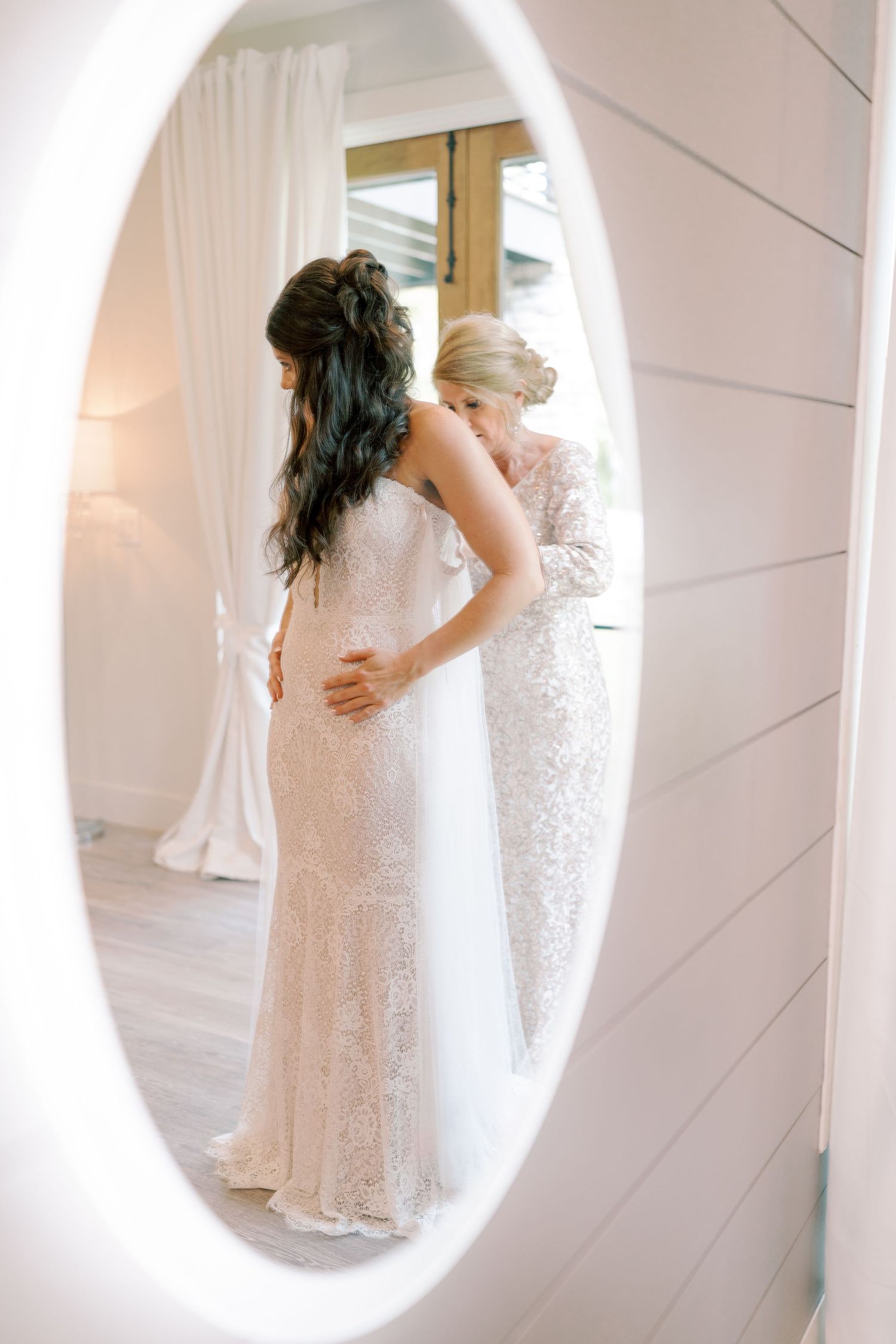 Elegant white wedding dress details captured in mirror reflections with soft lighting.