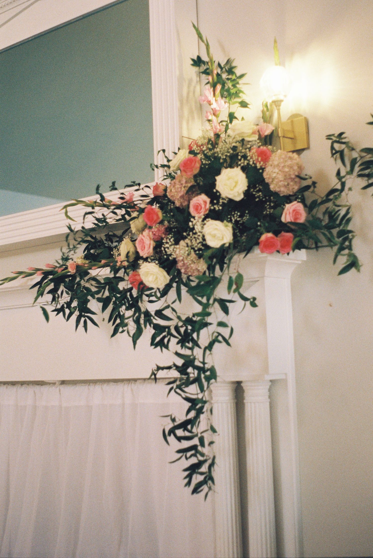 Elegant floral arrangements with pink and white flowers decorating white pillars at a wedding venue.