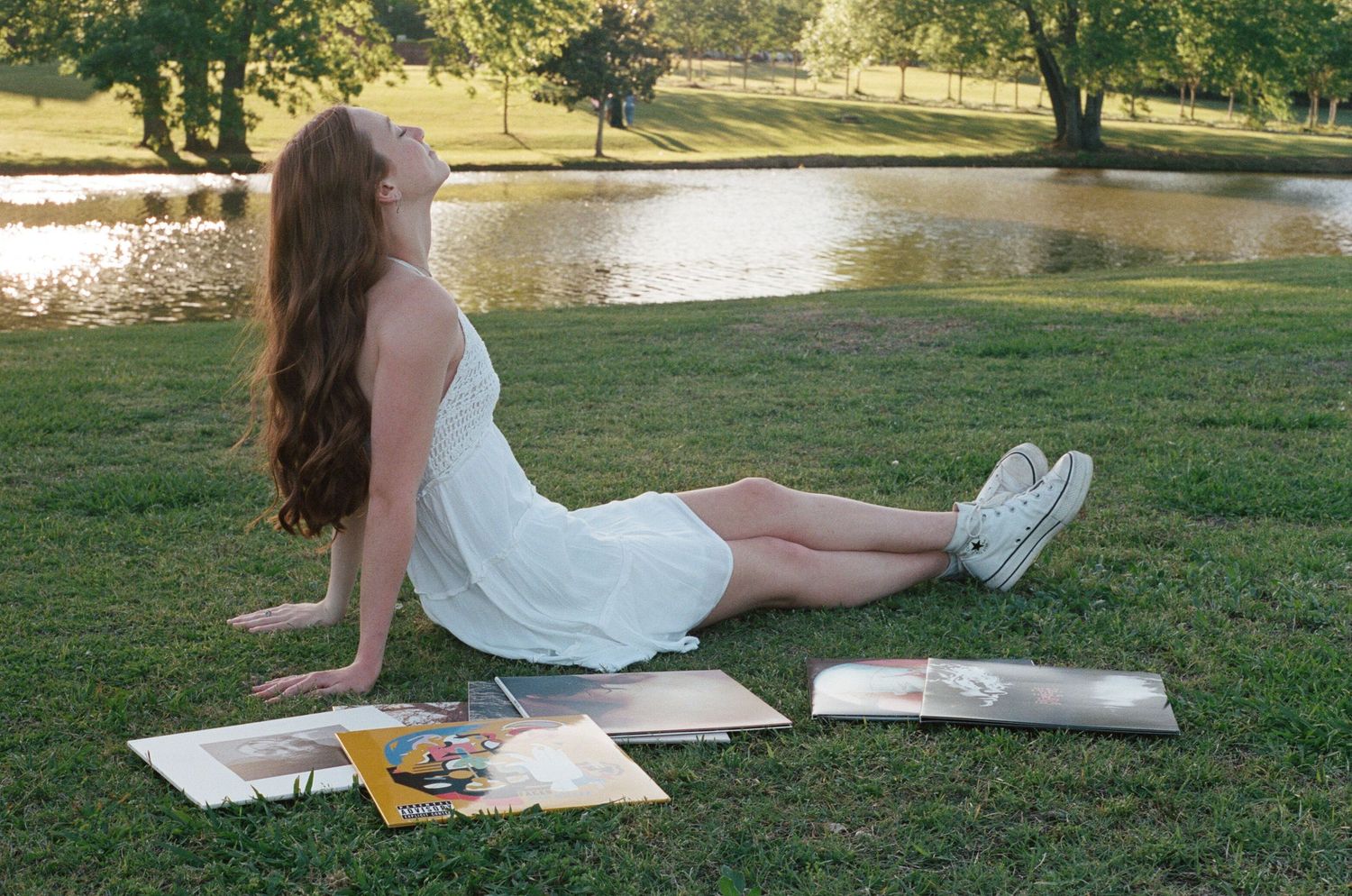 Graduate relaxing on grassy lawn during outdoor photo session.