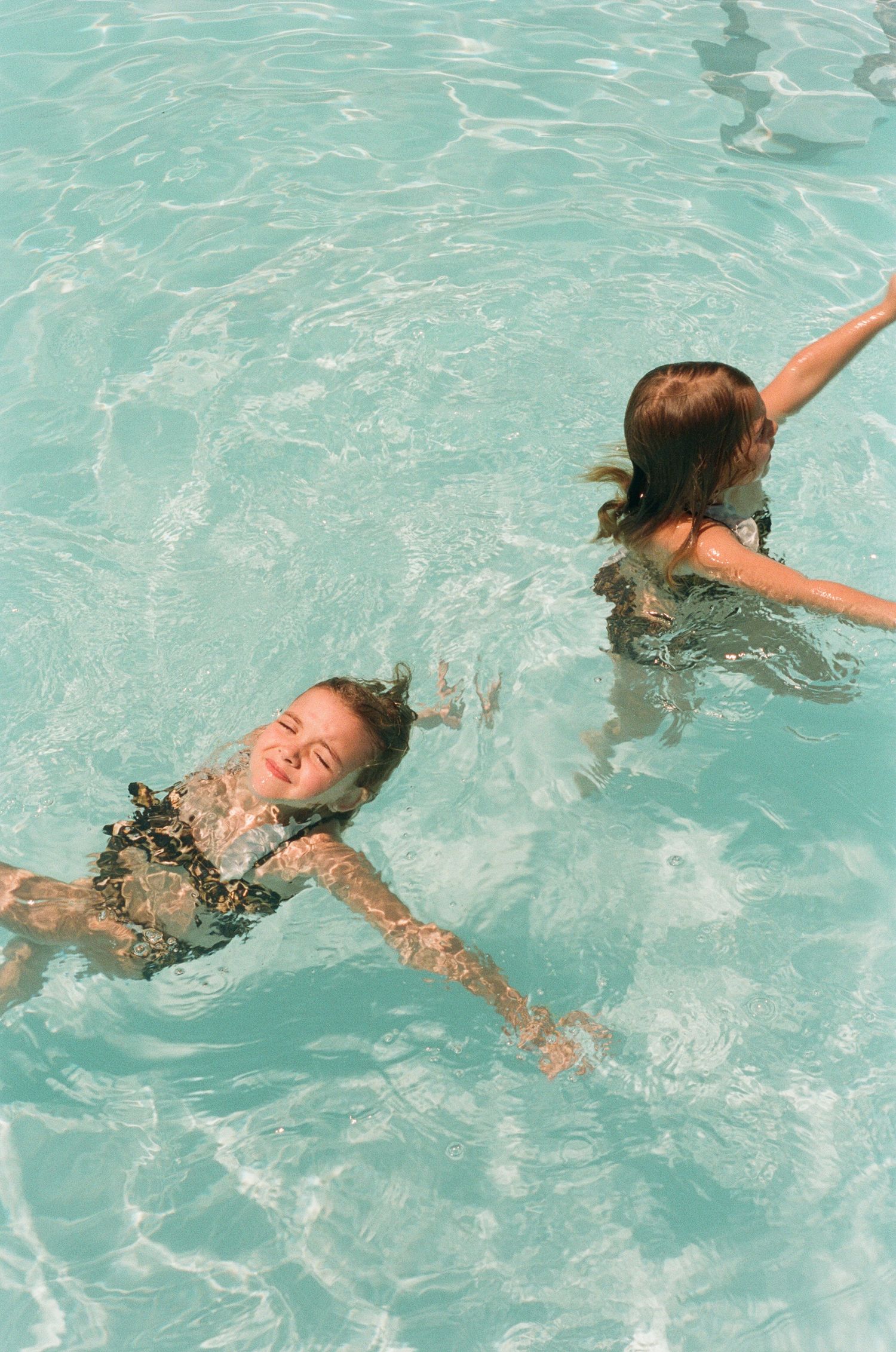 Swimming sequence showing a person floating and moving through turquoise pool water on a sunny day.