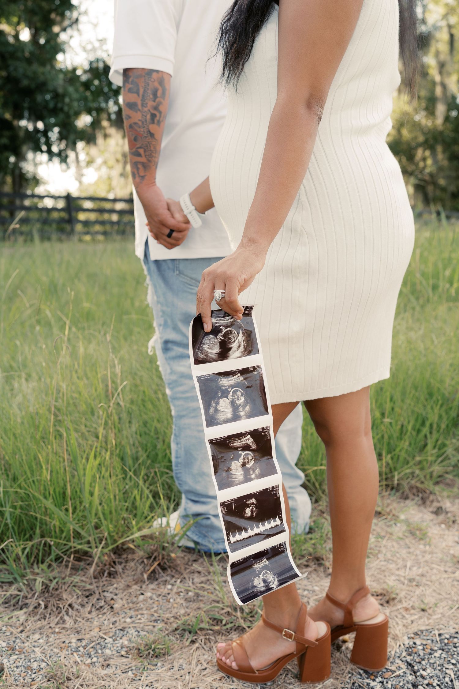 Ultrasound photos are displayed during an outdoor pregnancy announcement photoshoot.