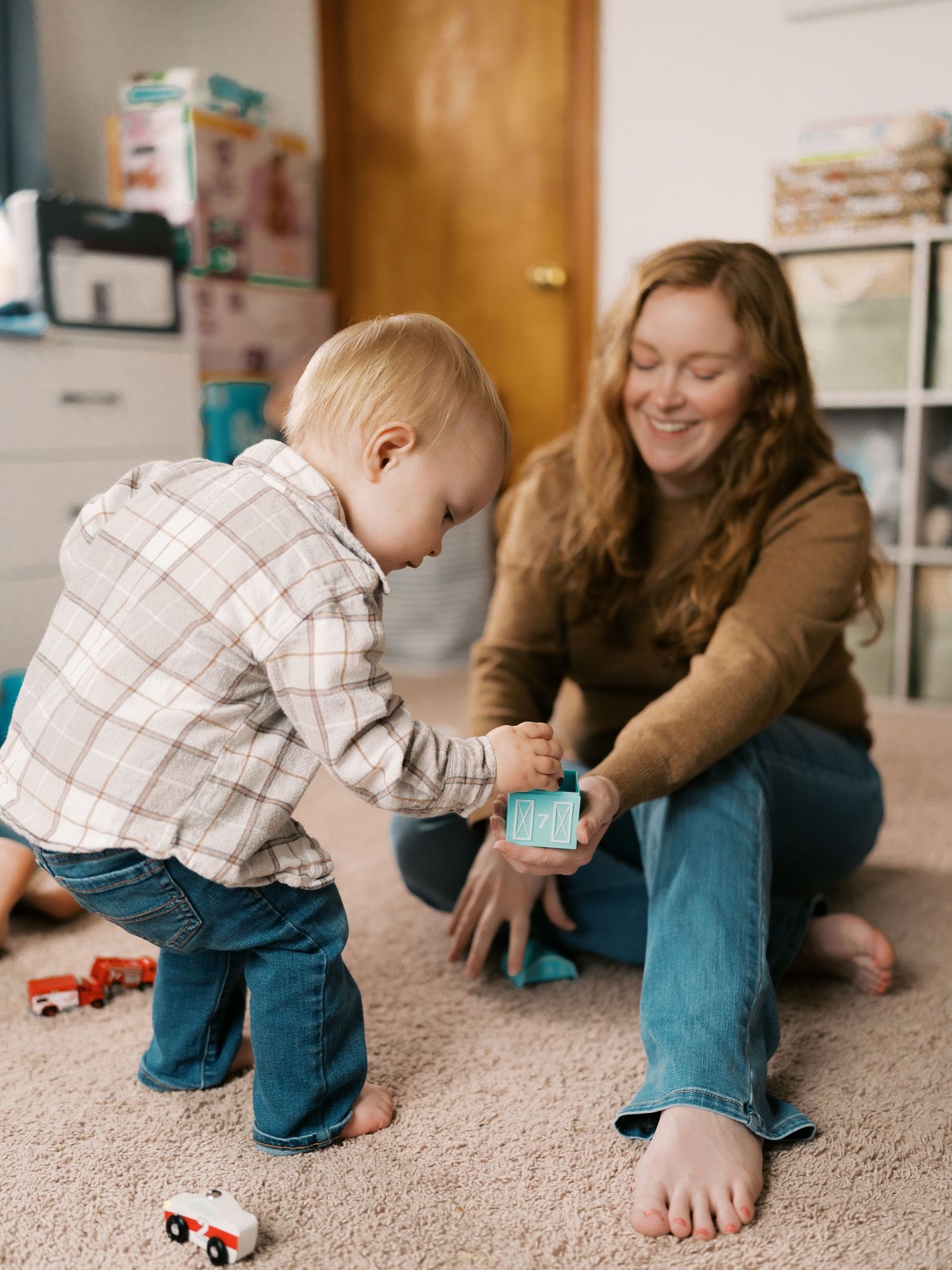 Family playtime on beige carpet with small child exploring toys.