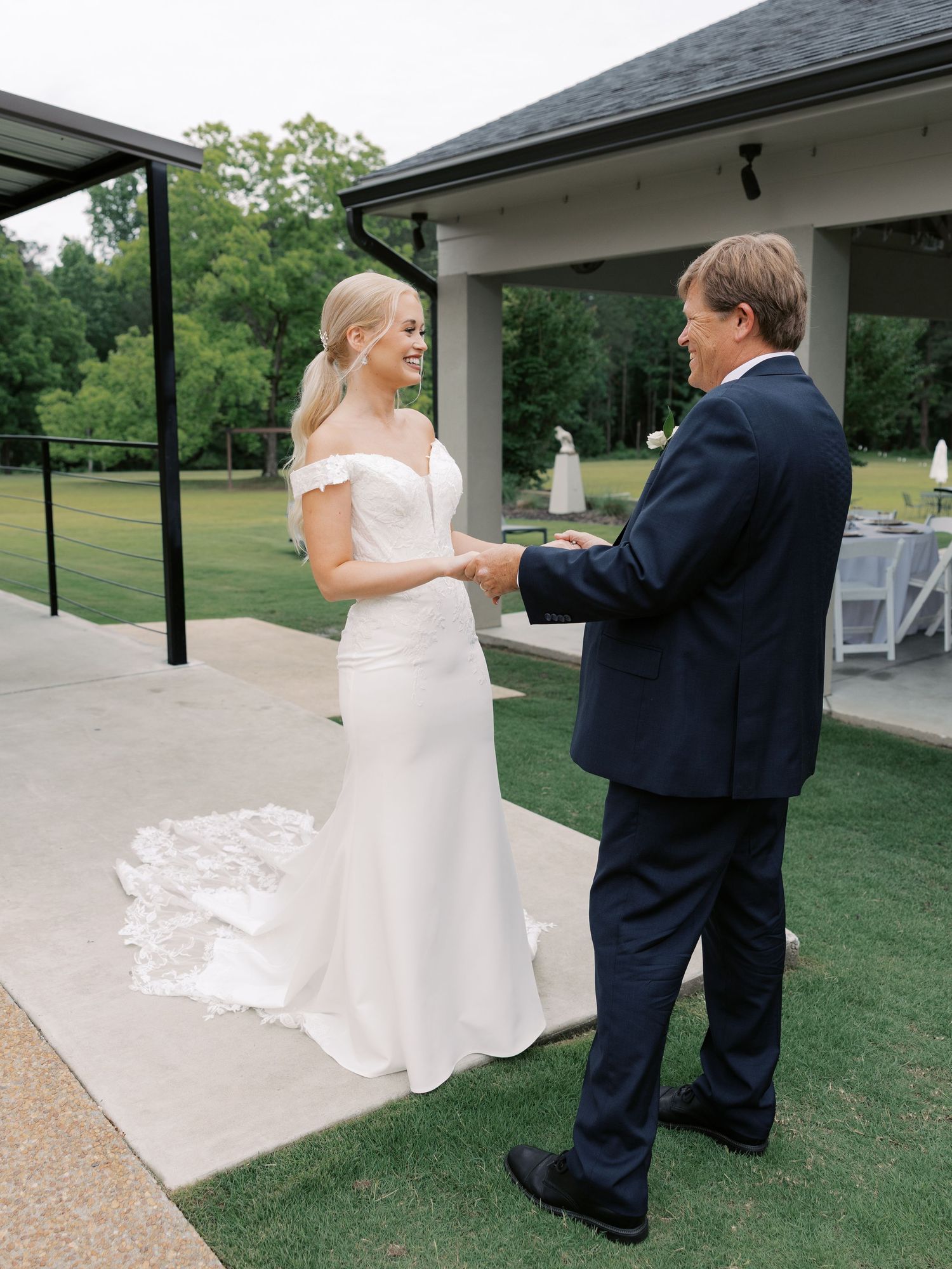 Wedding couple dancing together on an outdoor patio near a covered pavilion.