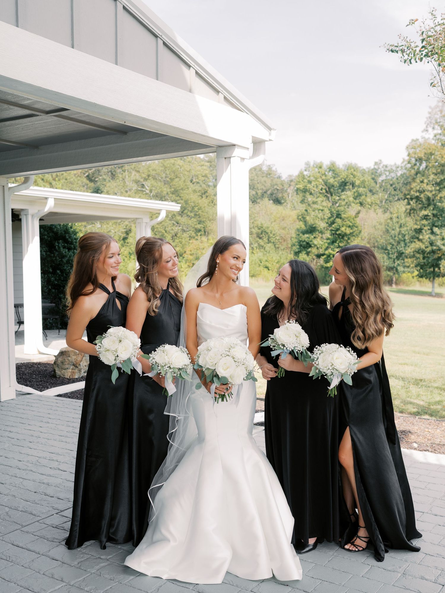 Bride in strapless white gown putting on earrings in rustic getting ready room.