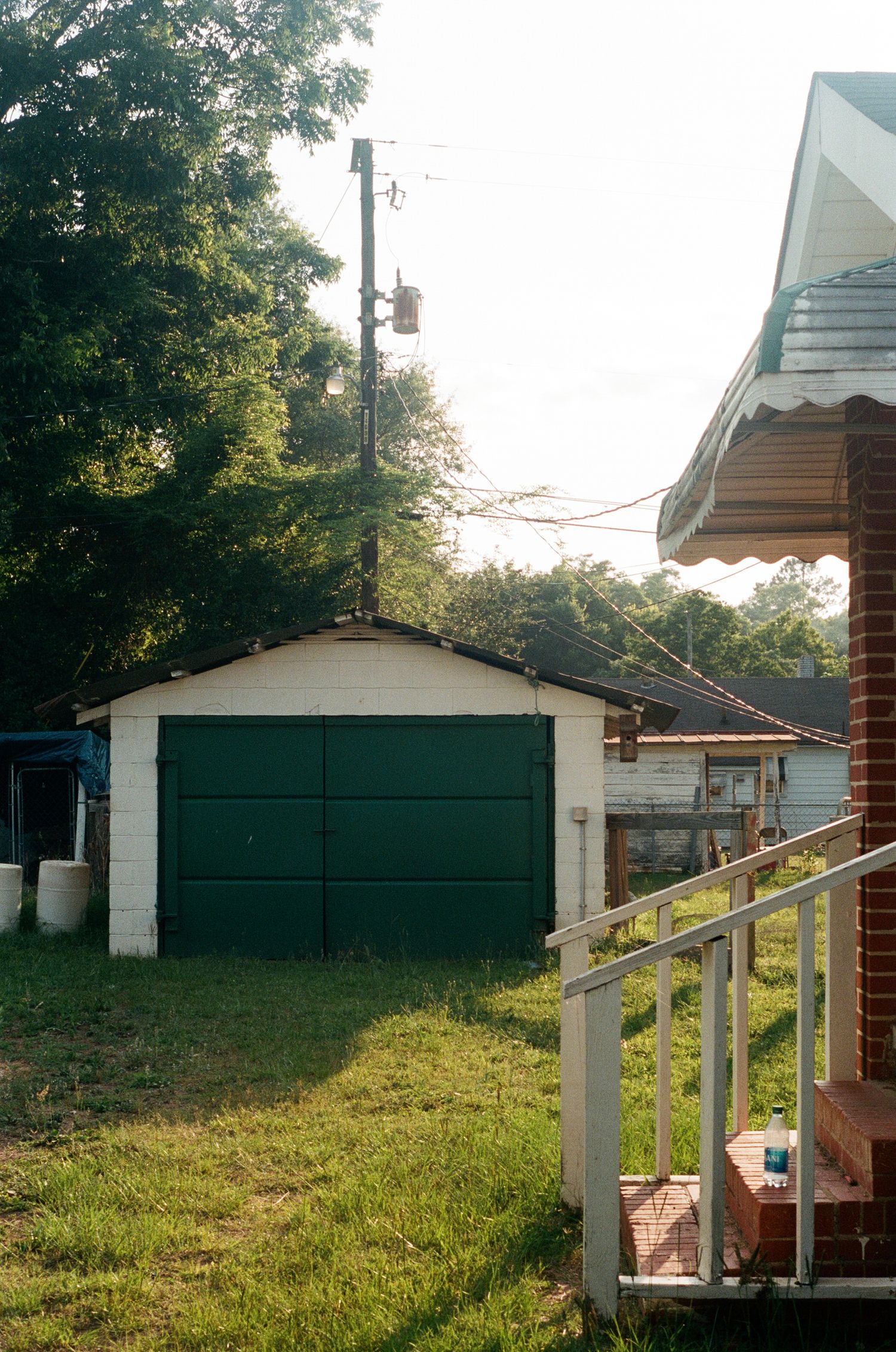 Panoramic view of a white house with green garage doors and grassy yard.
