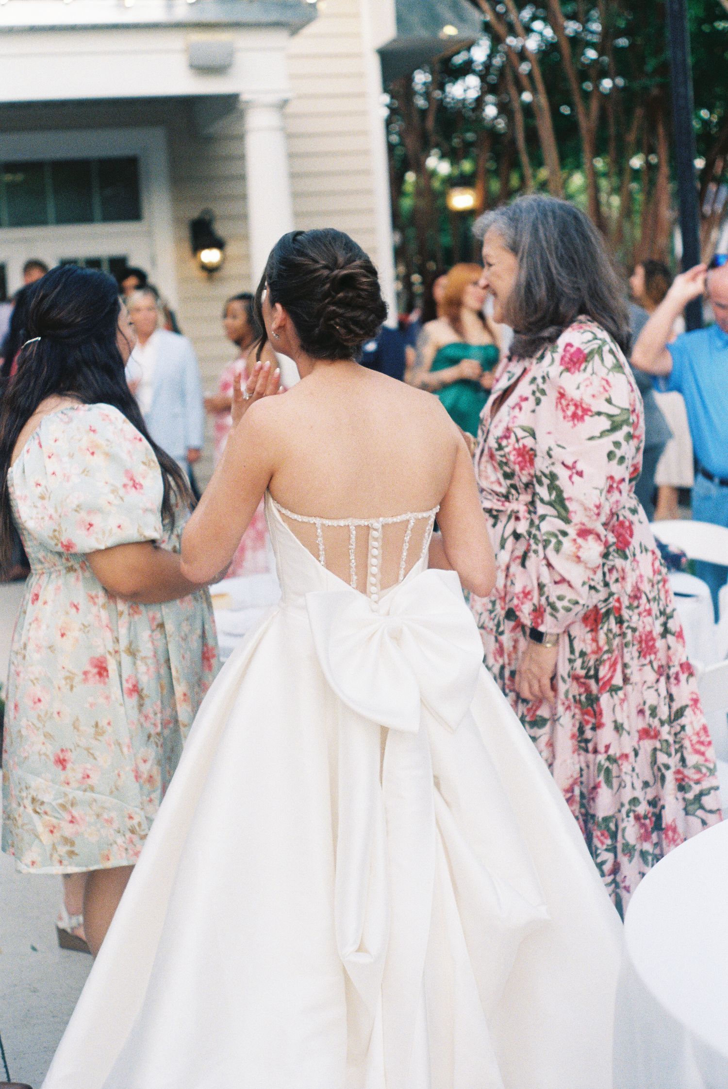 Bridesmaids wearing floral print dresses lined up at an outdoor wedding.