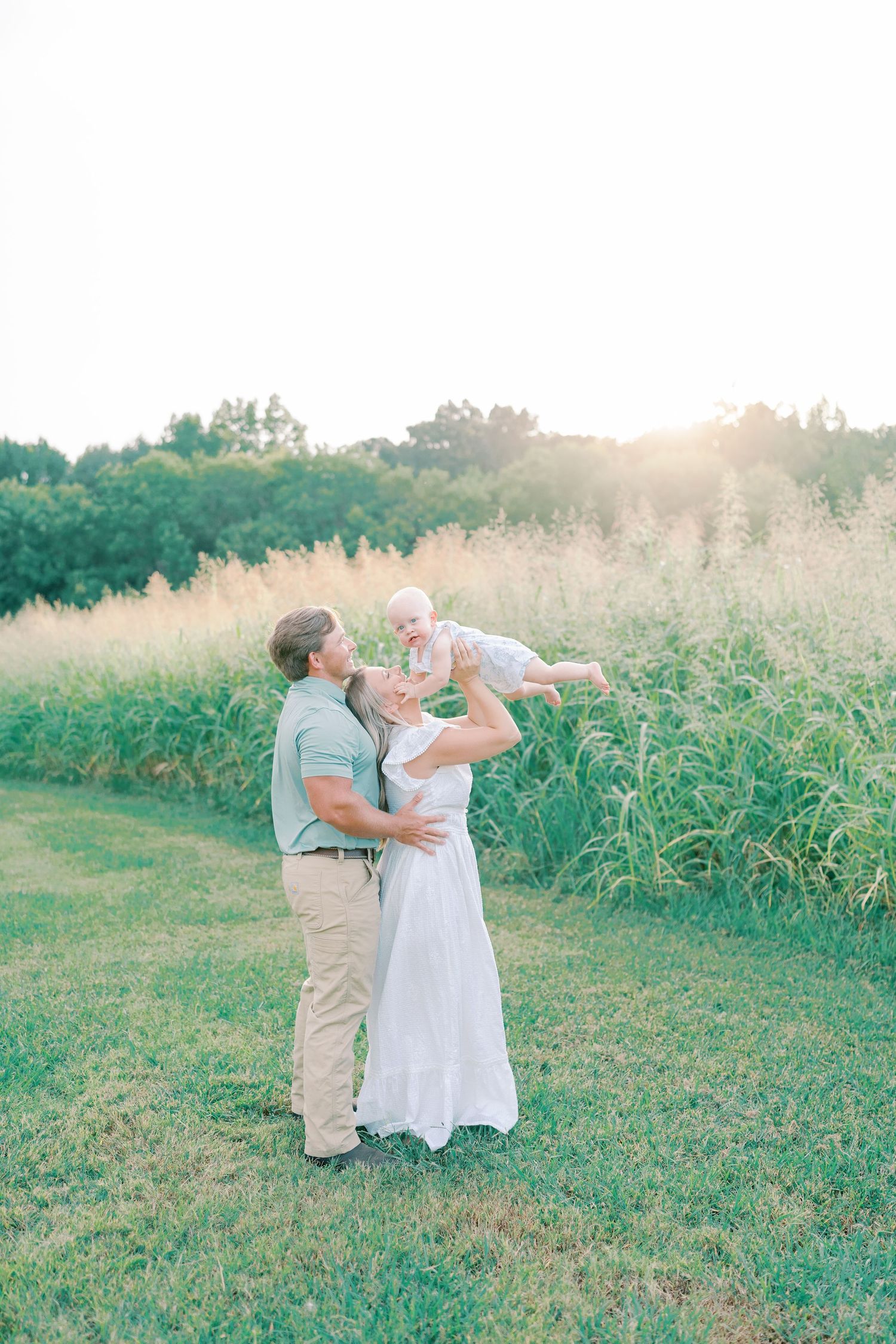 Couple dances together in a grassy field during a romantic sunset photo session.