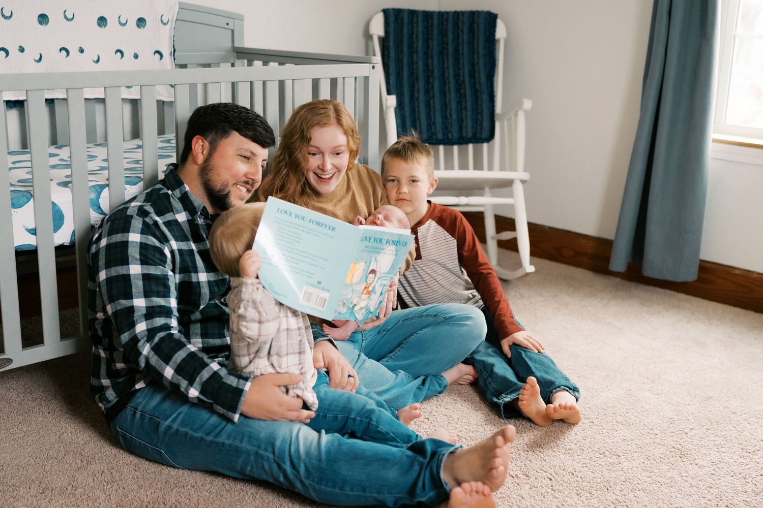 Family bonding moment while reading on carpet in nursery room.