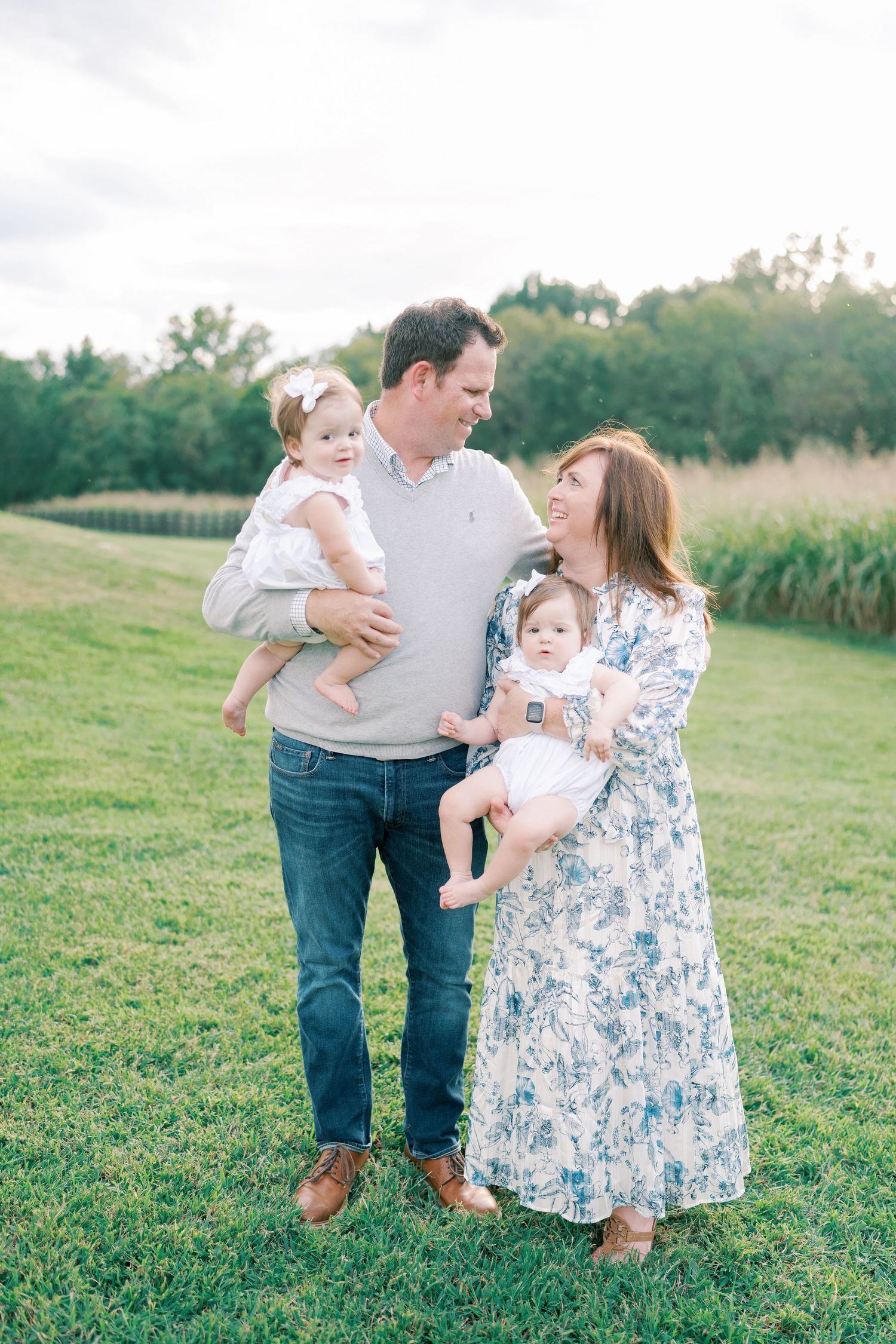 A family enjoys a playful moment together in a green field on a sunny day.