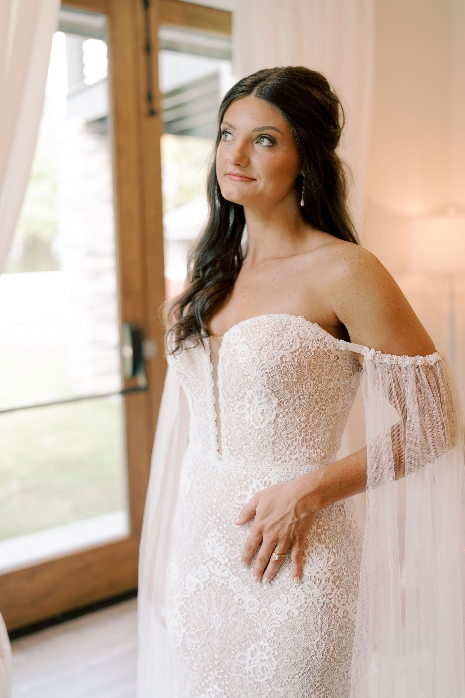 Close-up details of a delicate lace wedding dress with flowing tulle cape.