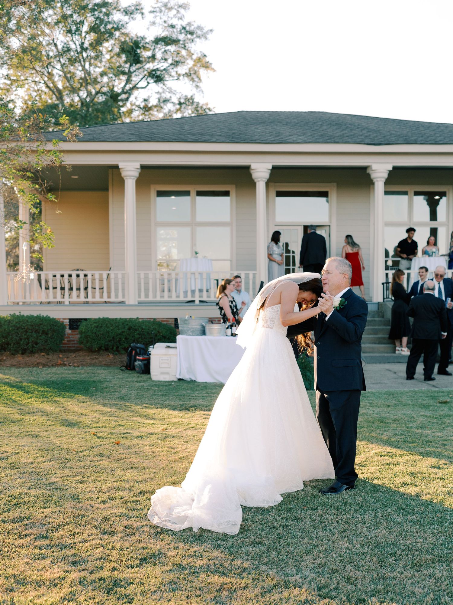 Elegant outdoor wedding reception setup with white decor against a classic colonial building backdrop.