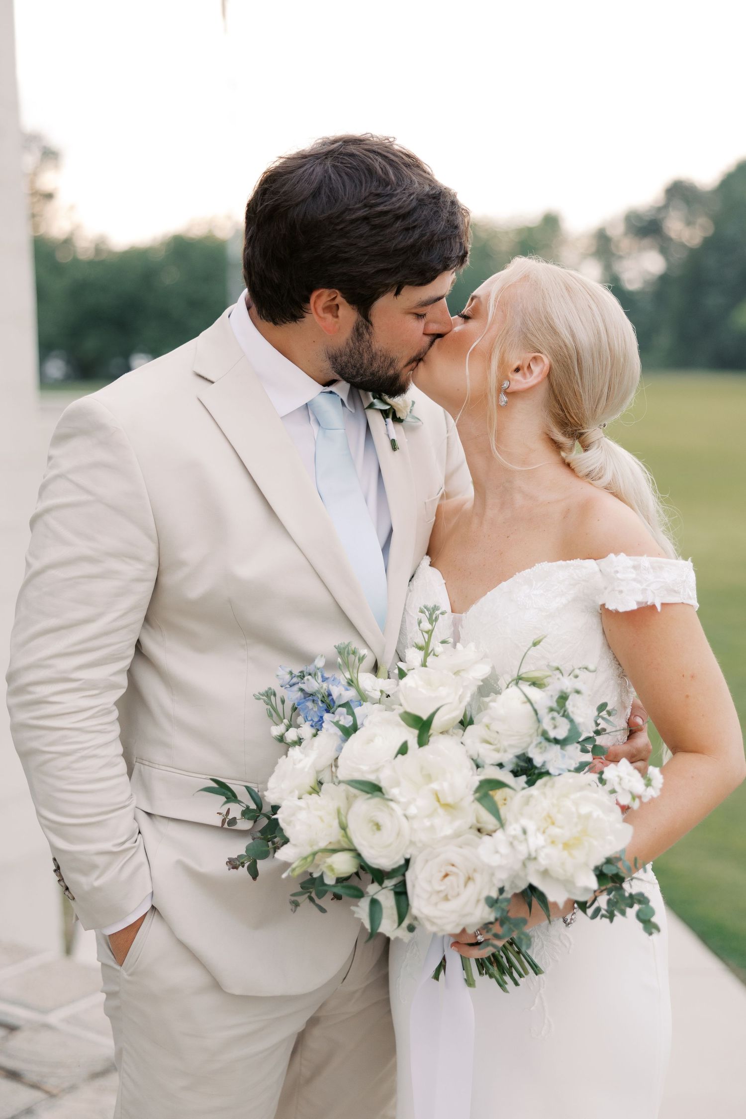 Wedding couple sharing romantic moment with white and blue floral bouquet.