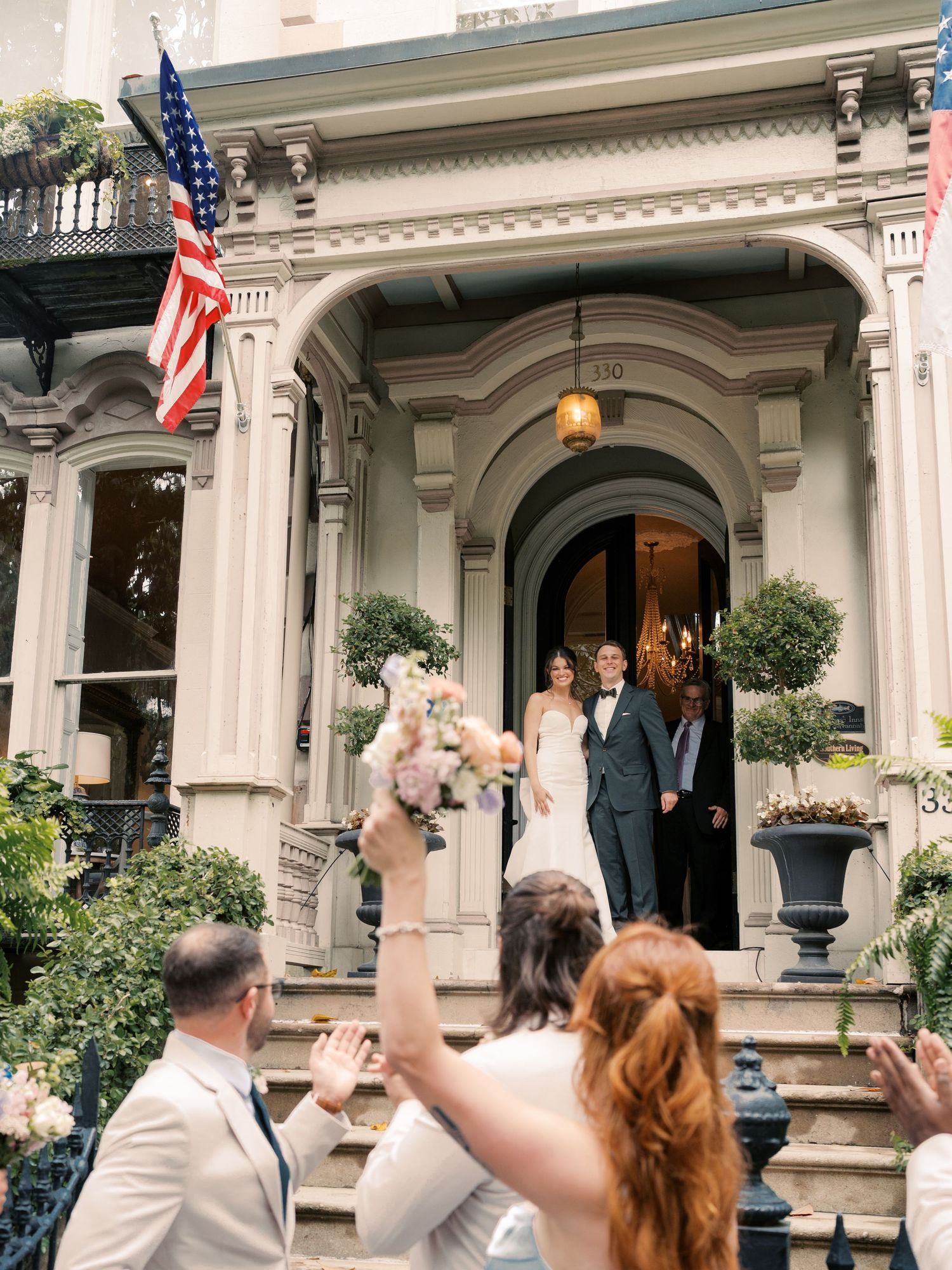 Guests celebrate outside a grand historic building with American flags and ornate architecture.