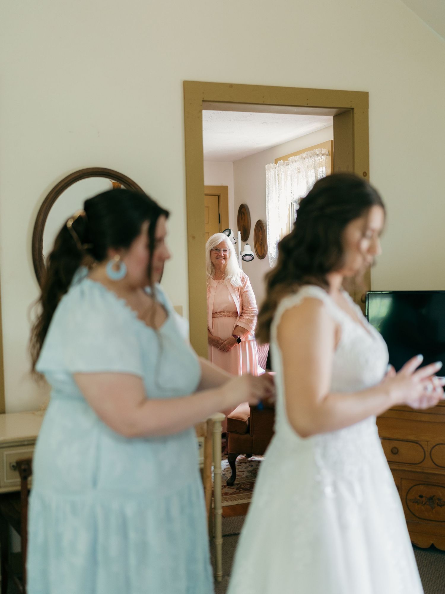 Two people in light blue dresses embrace during a wedding celebration.