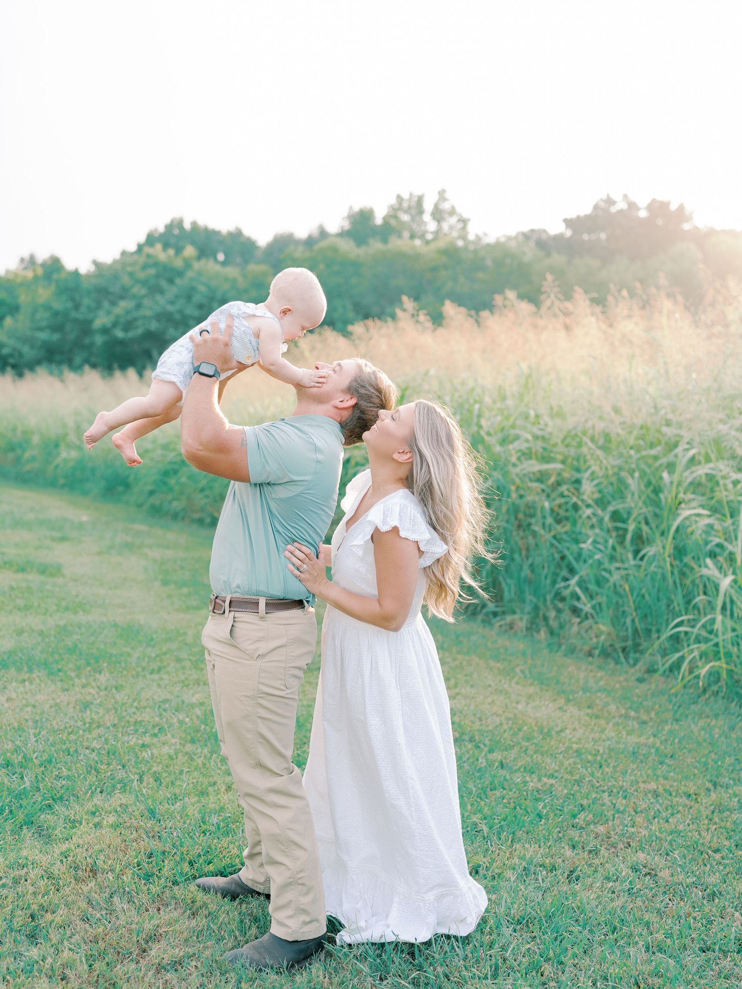 Couple shares romantic moments together in a sunlit field during sunset.