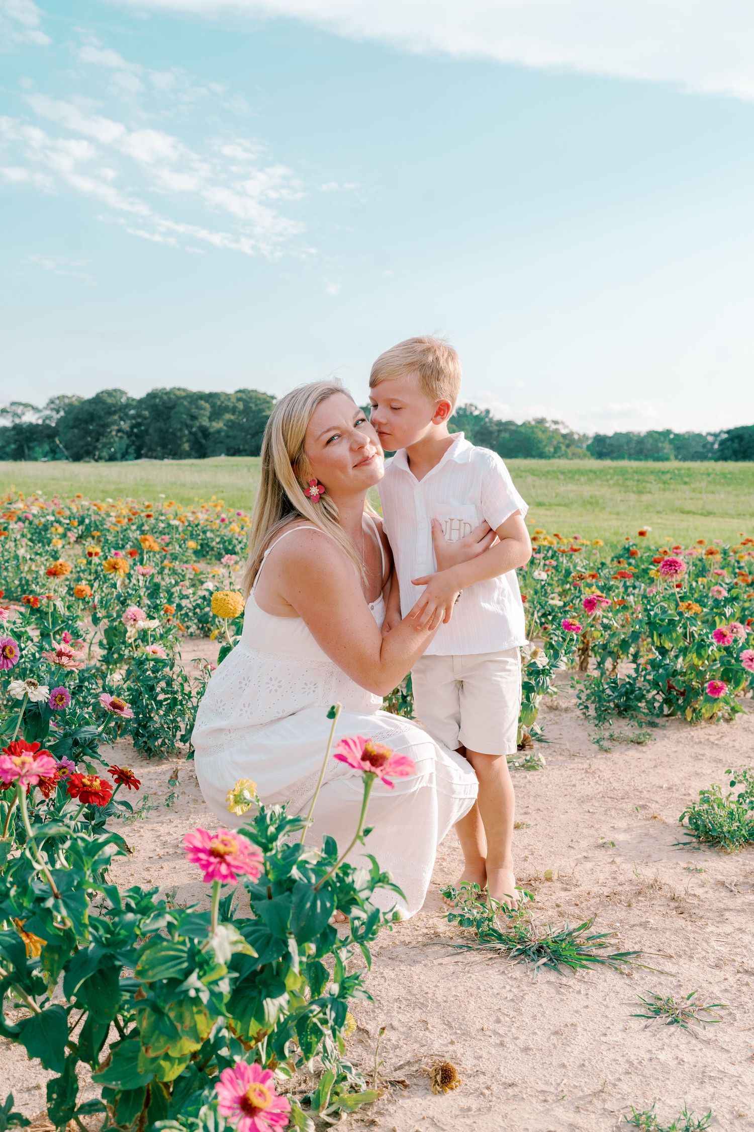 Two people share tender moments while exploring a colorful flower field on a bright day.