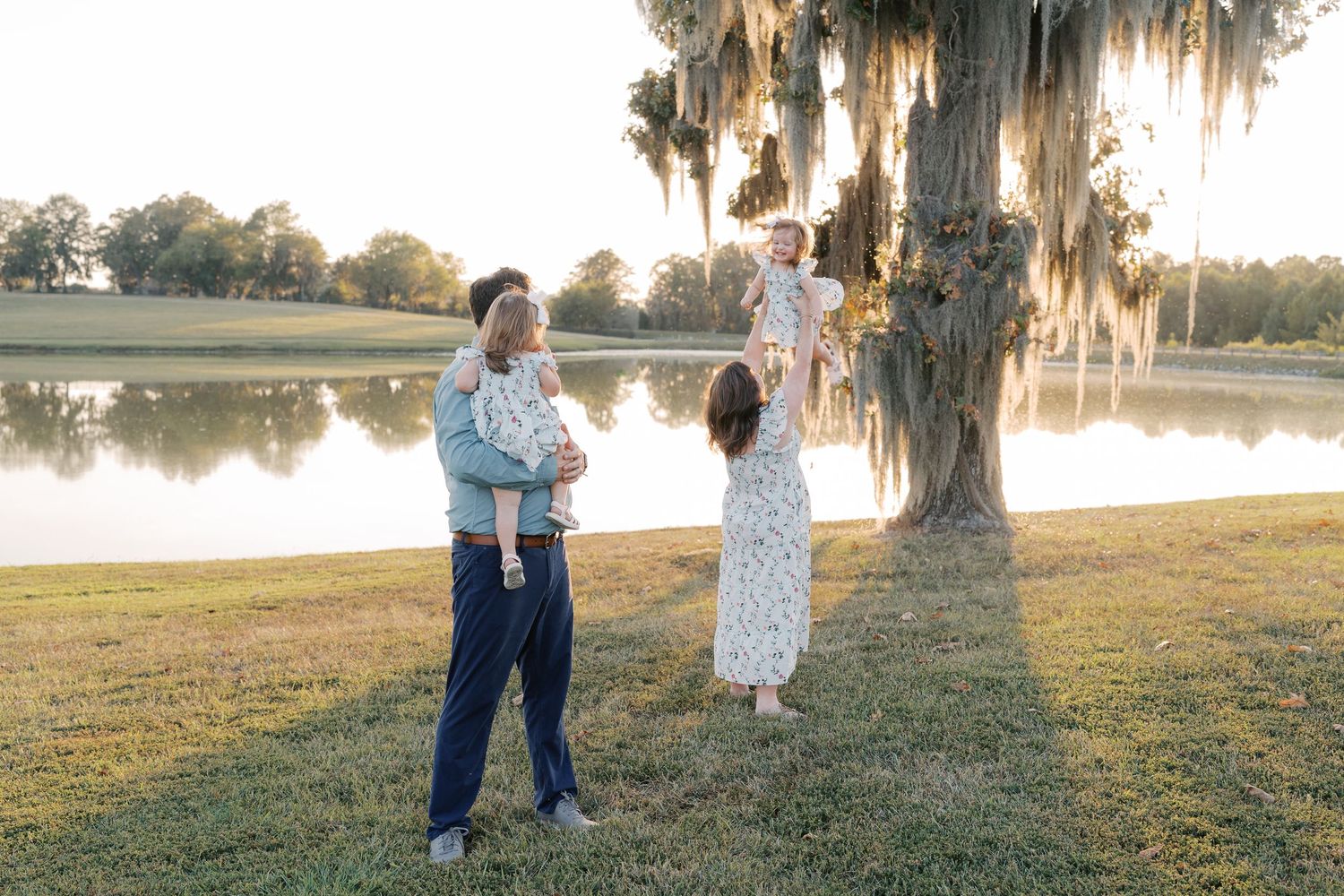Family photo session in a scenic field with Spanish moss hanging from trees.