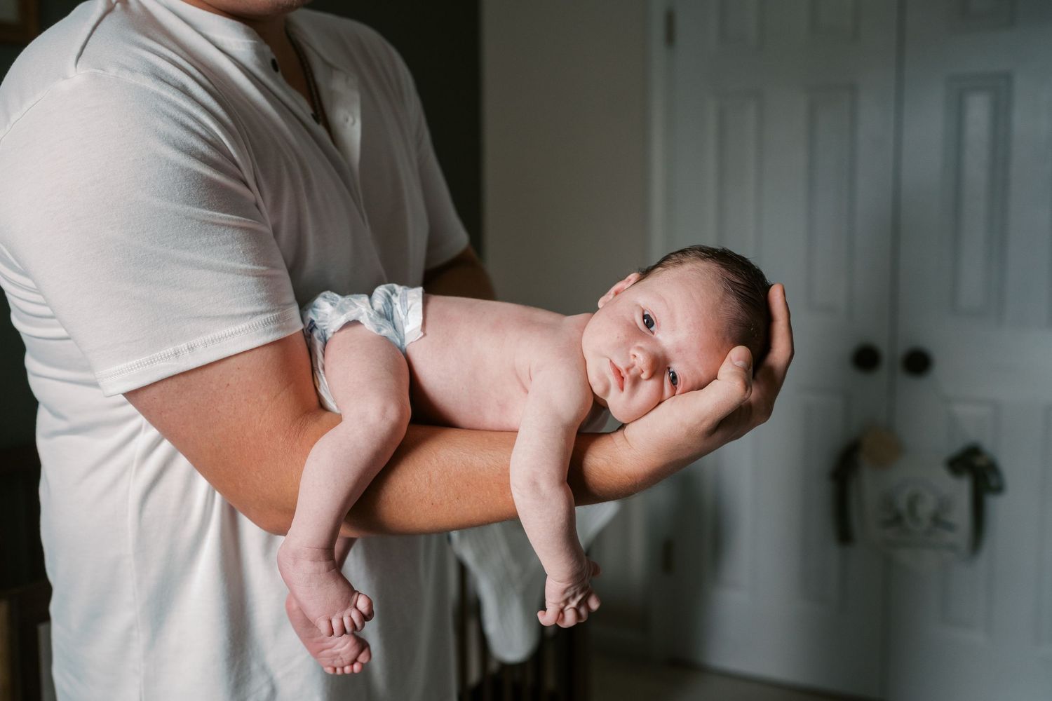 Close-up shots of gentle hands cradling a tiny newborn baby.