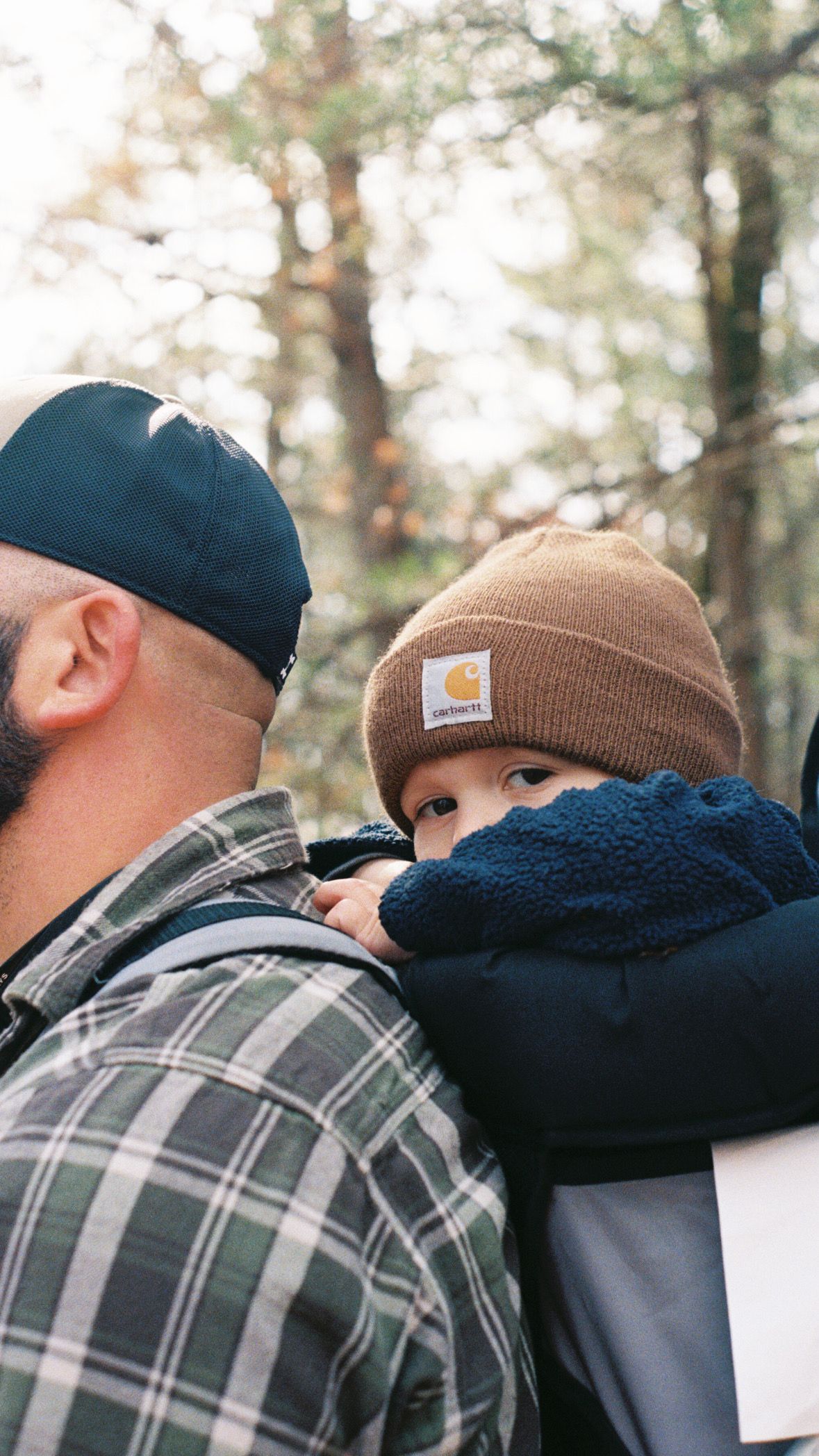 Tender moment between parent and child wearing winter hats outdoors.