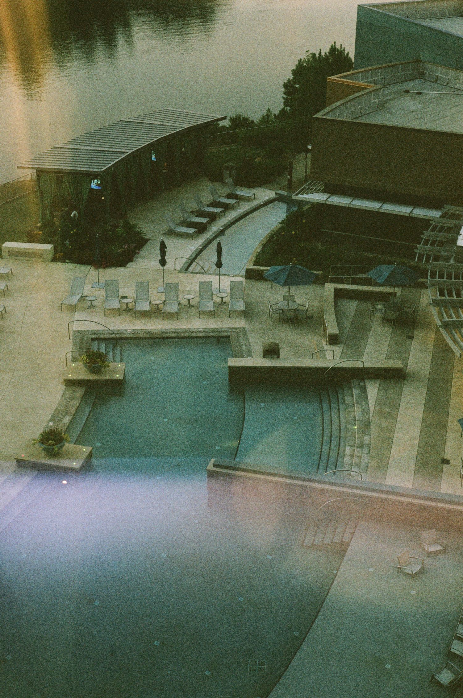 Aerial view of a large outdoor swimming pool complex at dusk.