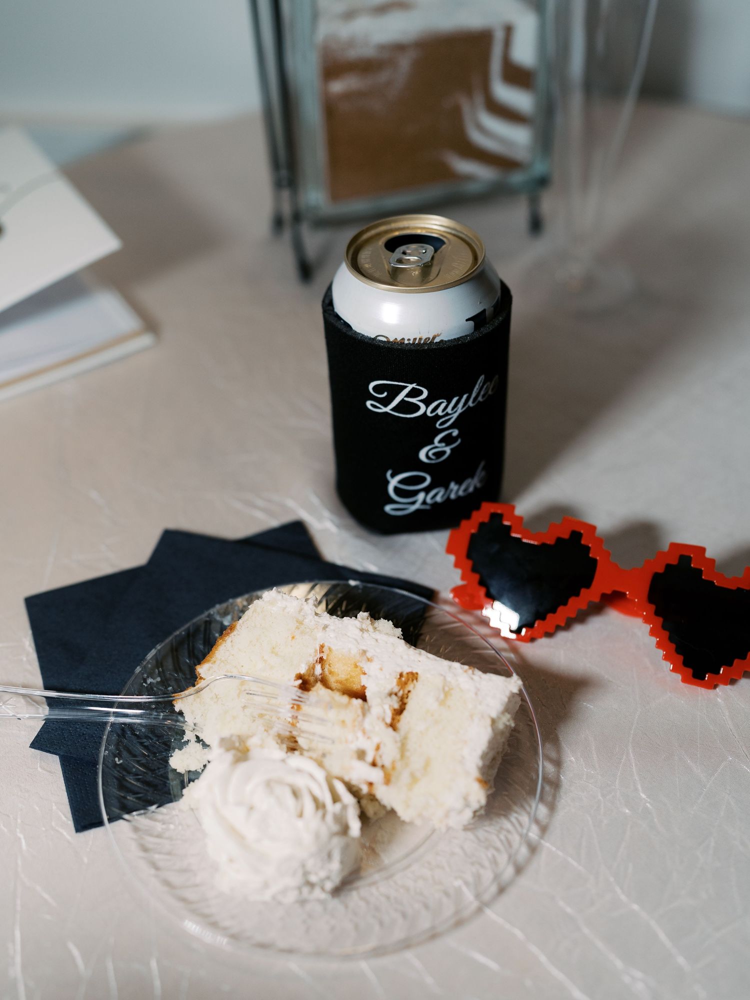 Wedding reception details with black drink koozies and decorative elements on white surface.