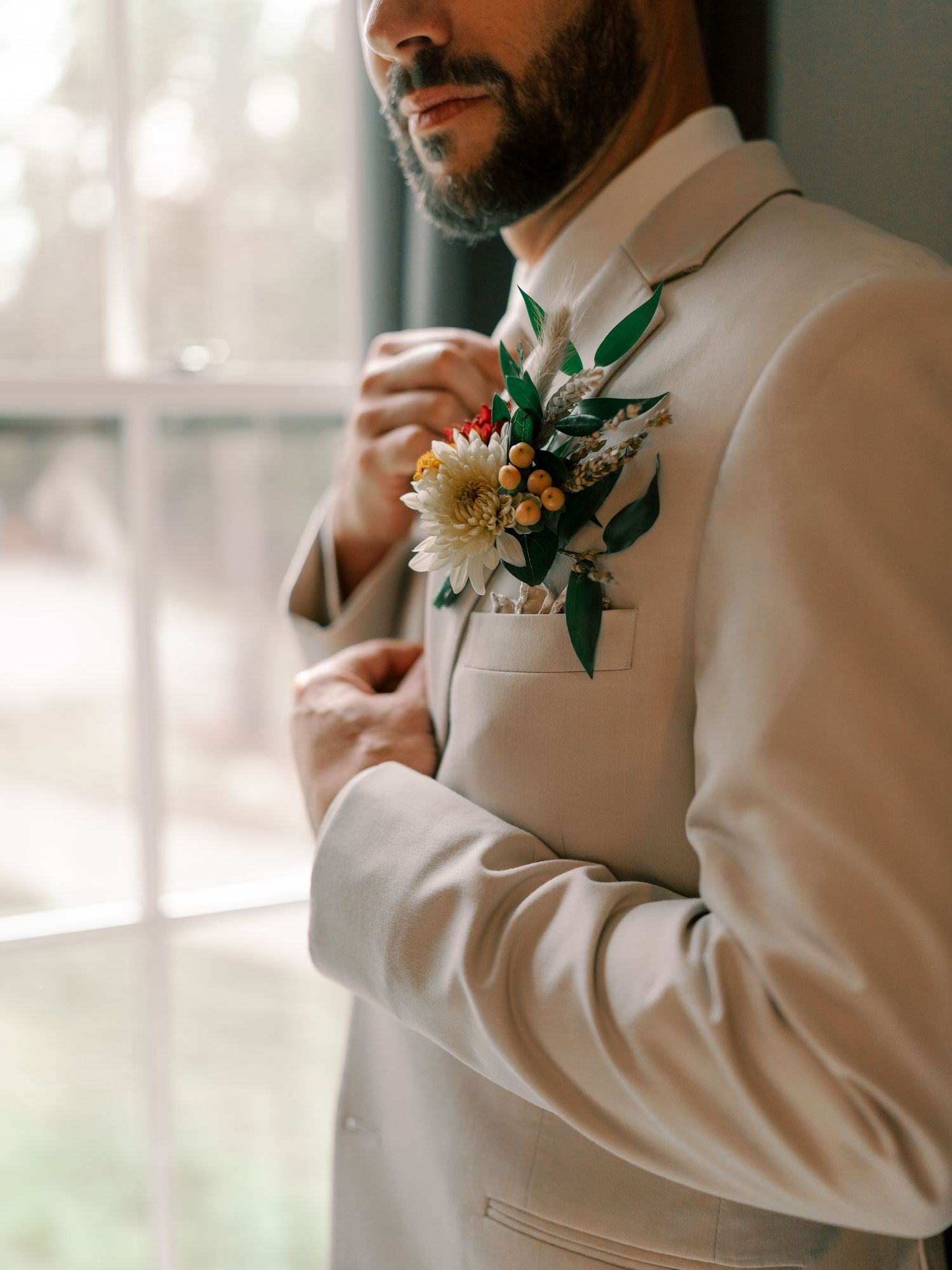 Close-up details of groom's cream suit with floral boutonniere.